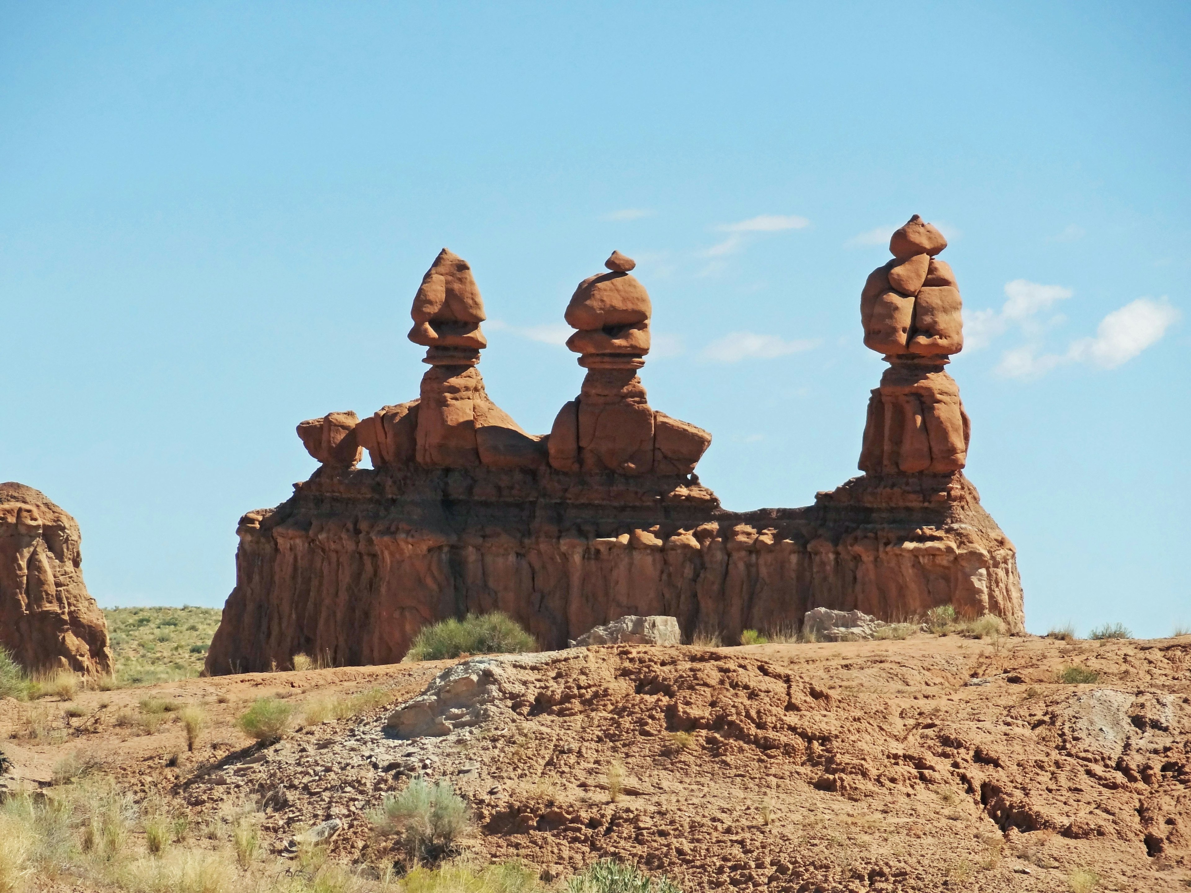 Three distinctive rock formations standing on a reddish landscape