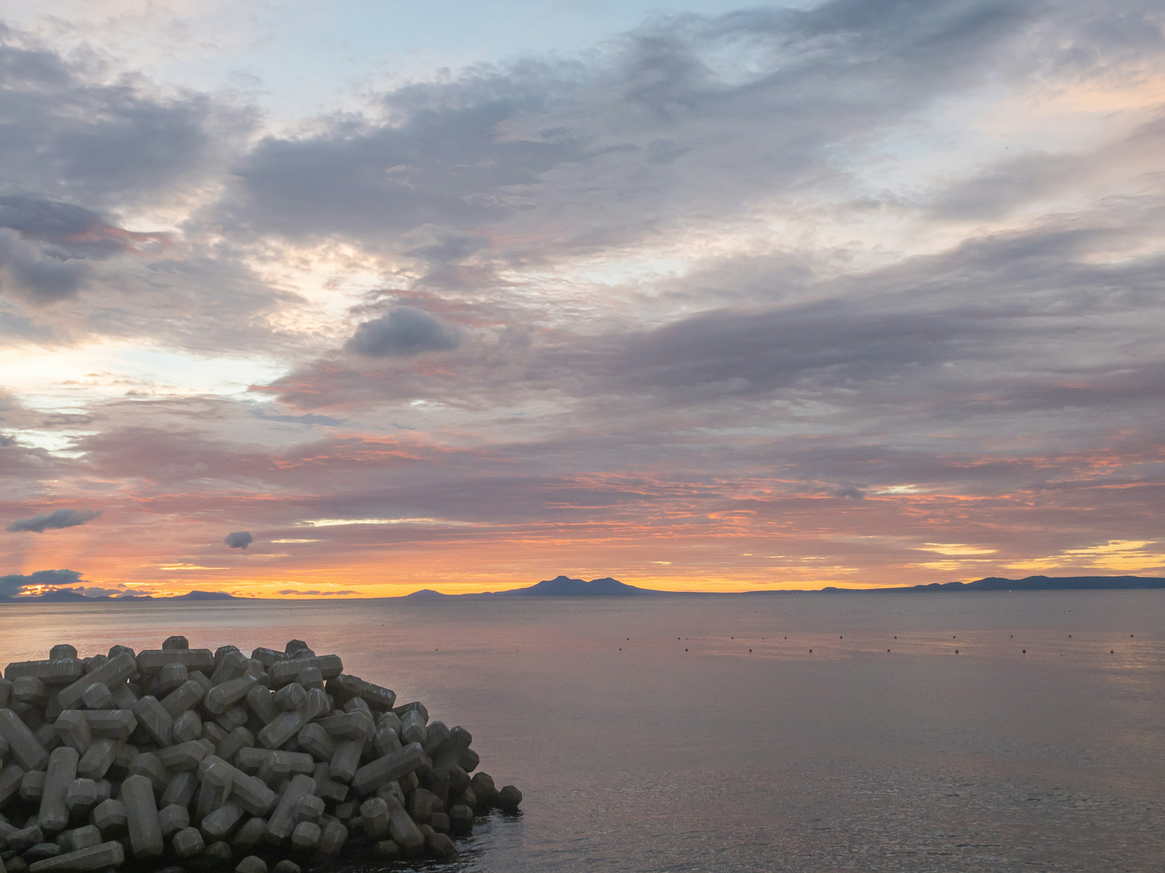 Hermosa puesta de sol sobre el mar con un rompeolas de piedra