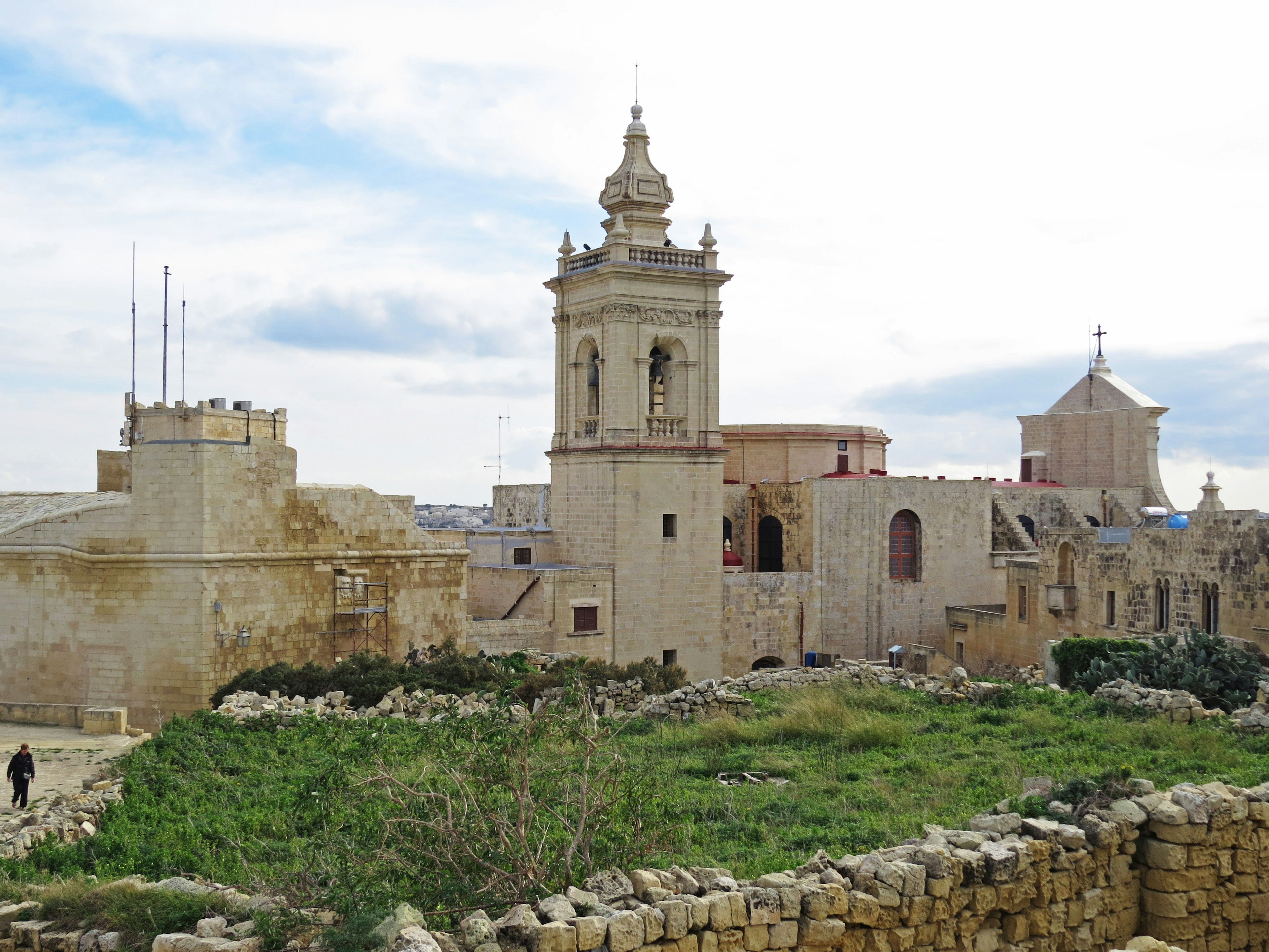 Historic buildings with a tower surrounded by greenery and blue sky