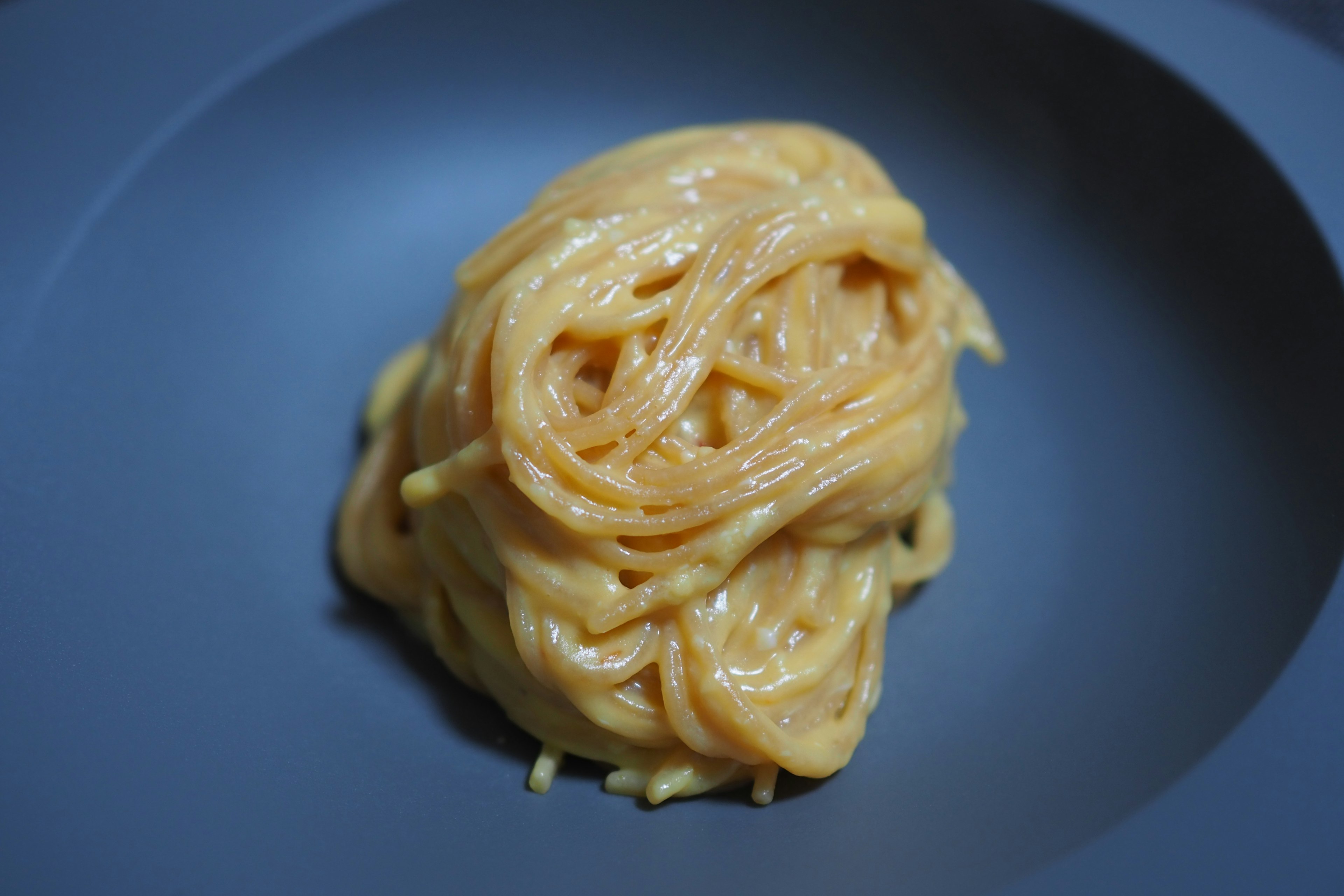 Cremige Spaghetti auf einem tiefblauen Teller serviert