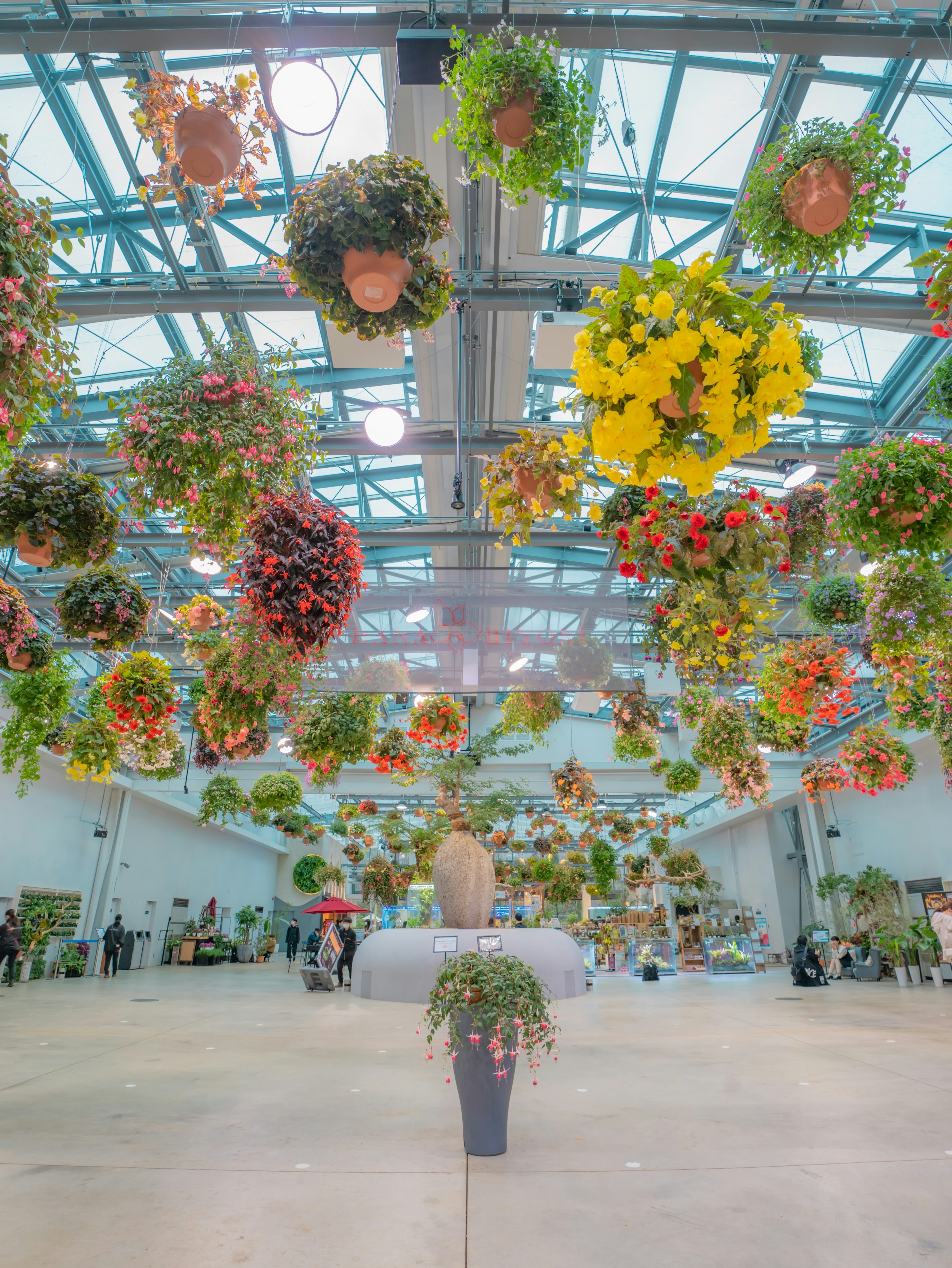 Espace intérieur lumineux décoré de fleurs suspendues évoquant une exposition florale