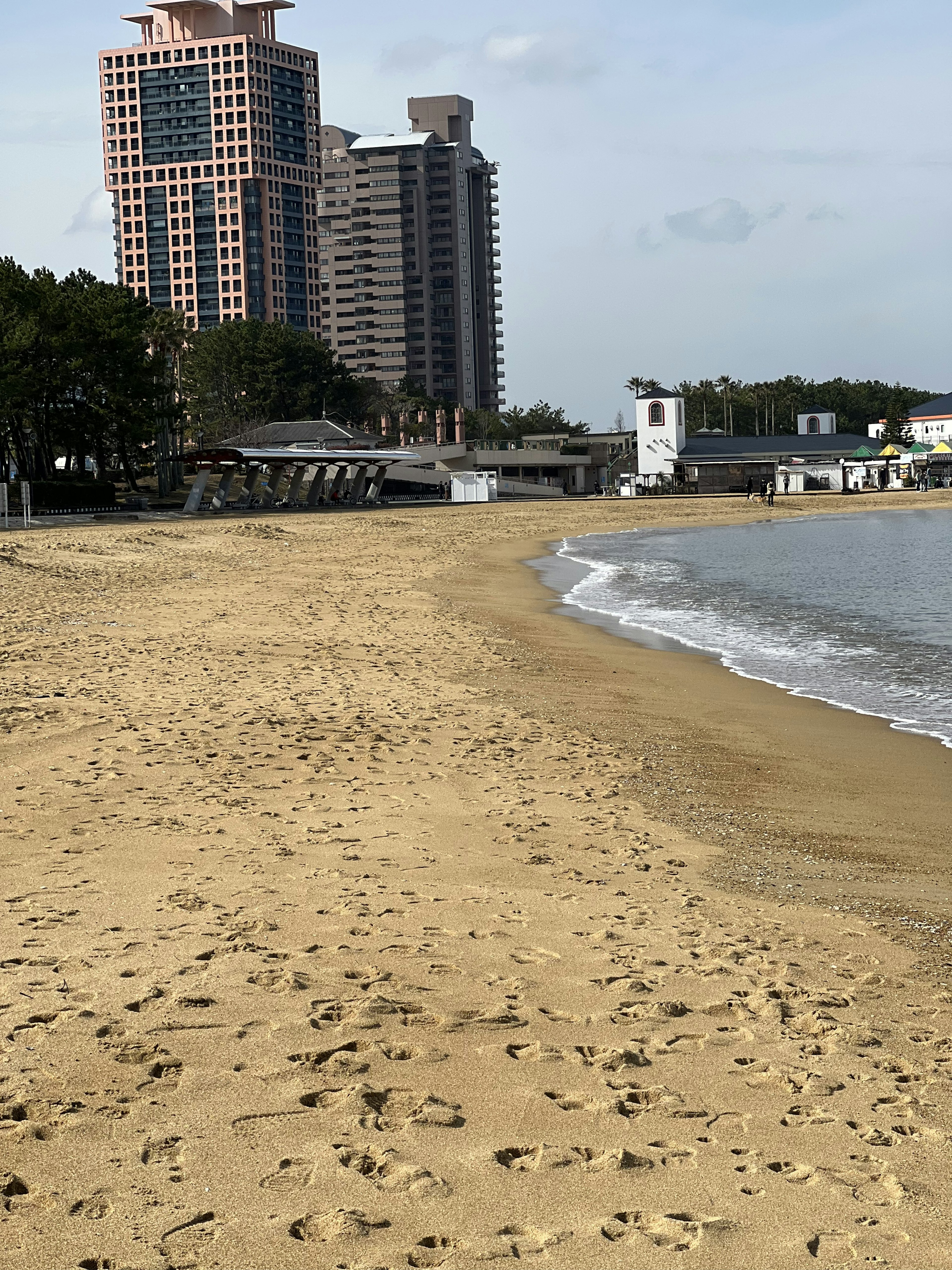 Beach shoreline with footprints and tall buildings in the background