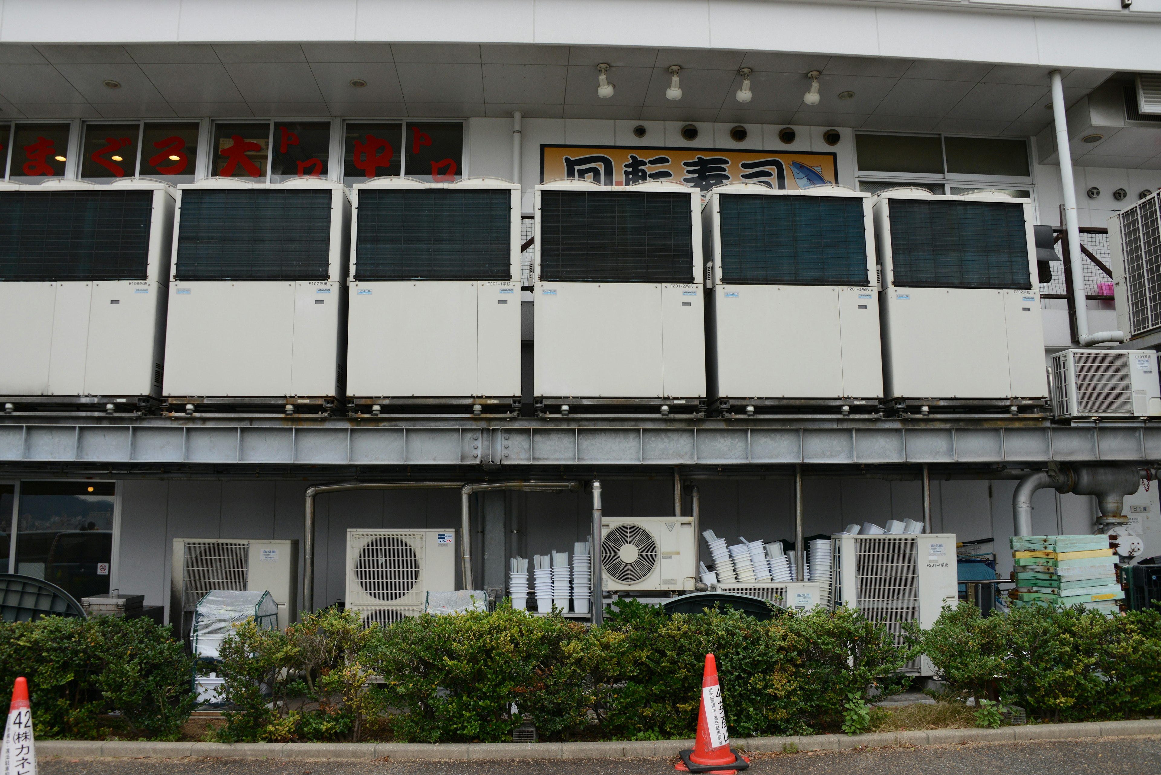 Exterior of a commercial building featuring white refrigerators and air conditioning units