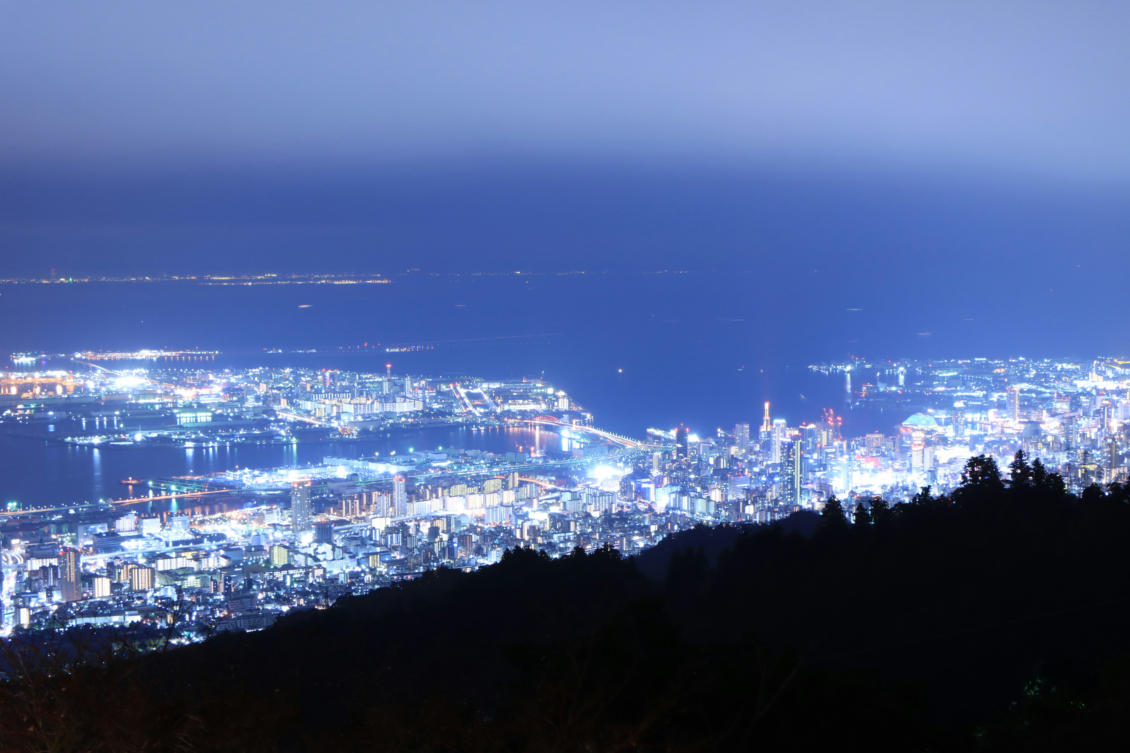 Vista notturna di una città e del mare illuminata dalle luci brillanti del porto