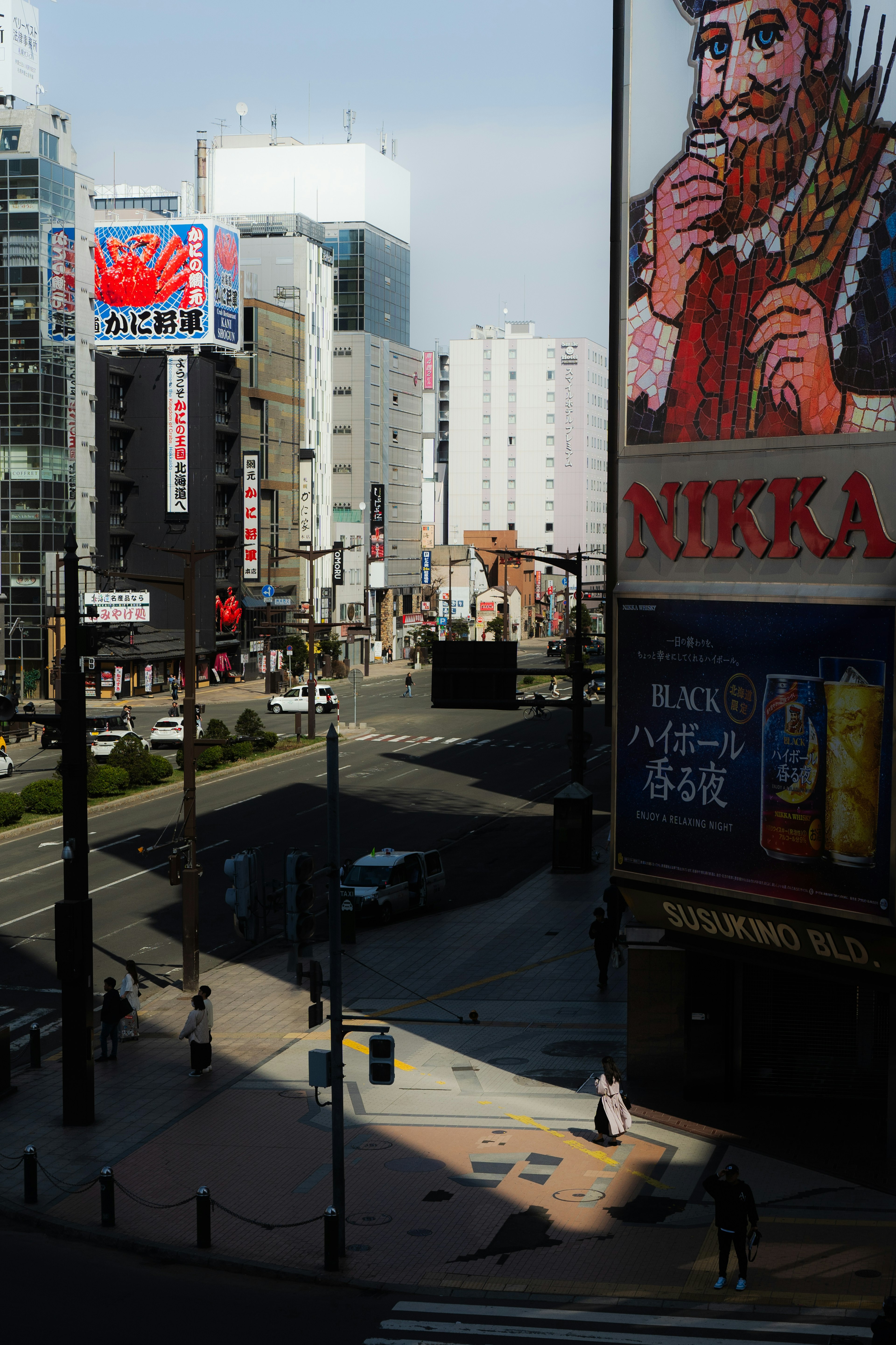 City intersection featuring large advertising billboards and pedestrians