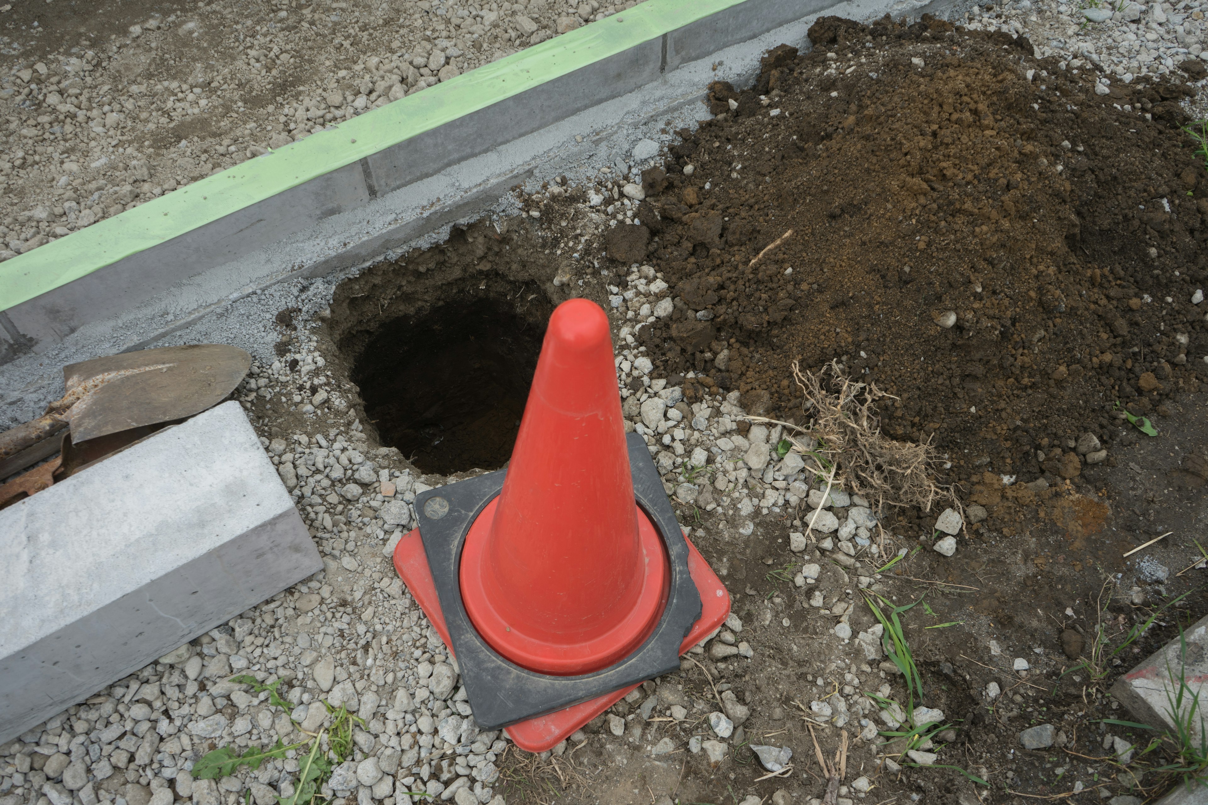 Construction site with an orange cone and a hole in the ground