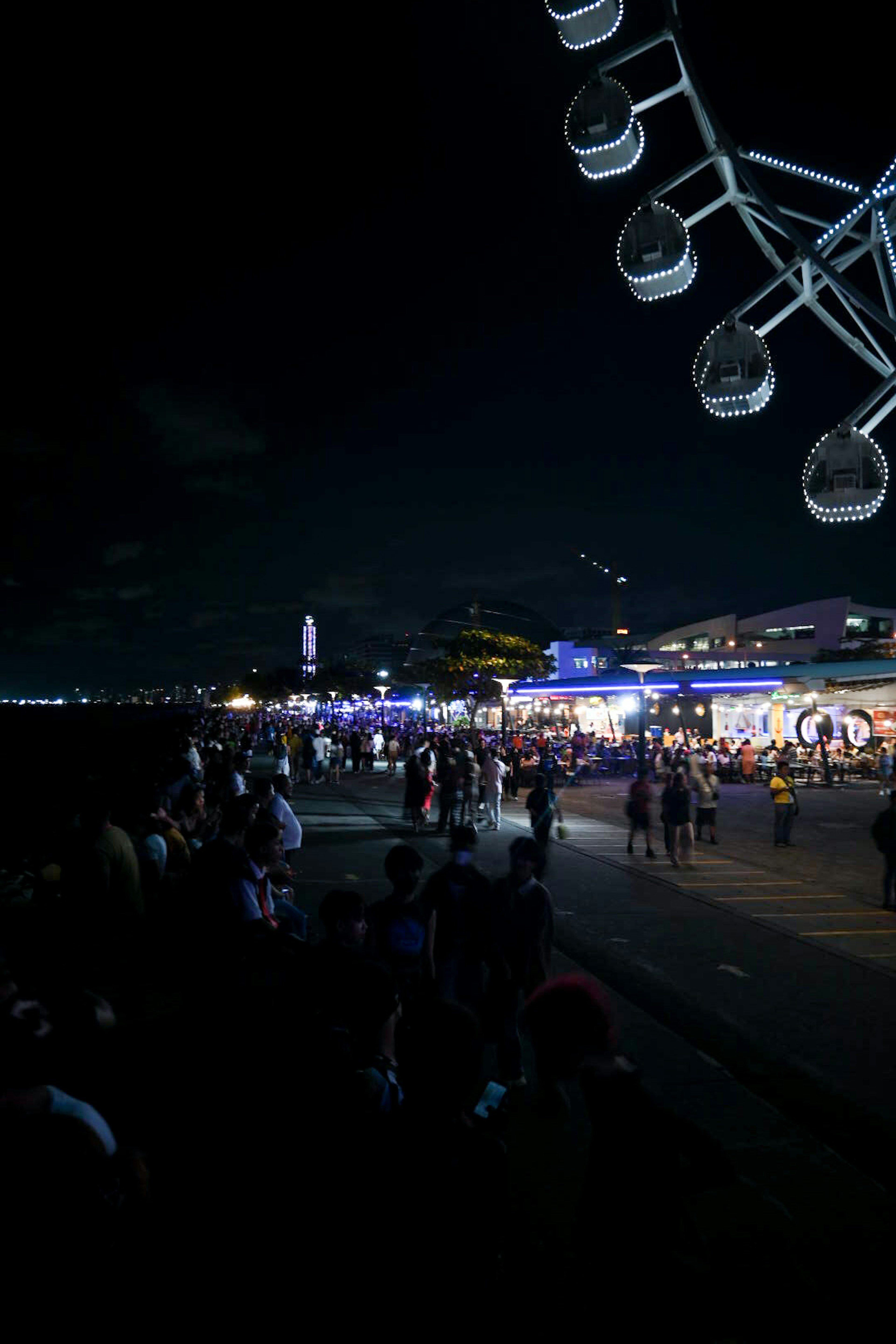 Pemandangan malam hari dari roda ferris dan tepi laut yang ramai