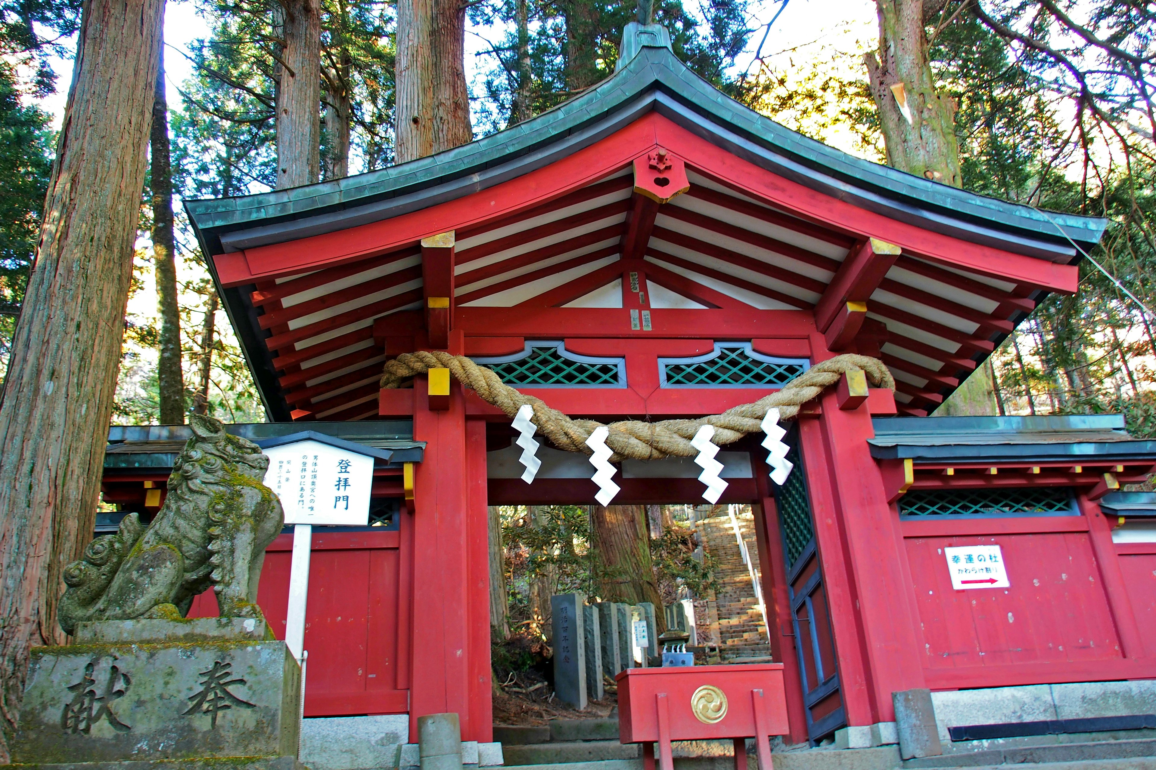 Puerta del santuario roja rodeada de árboles