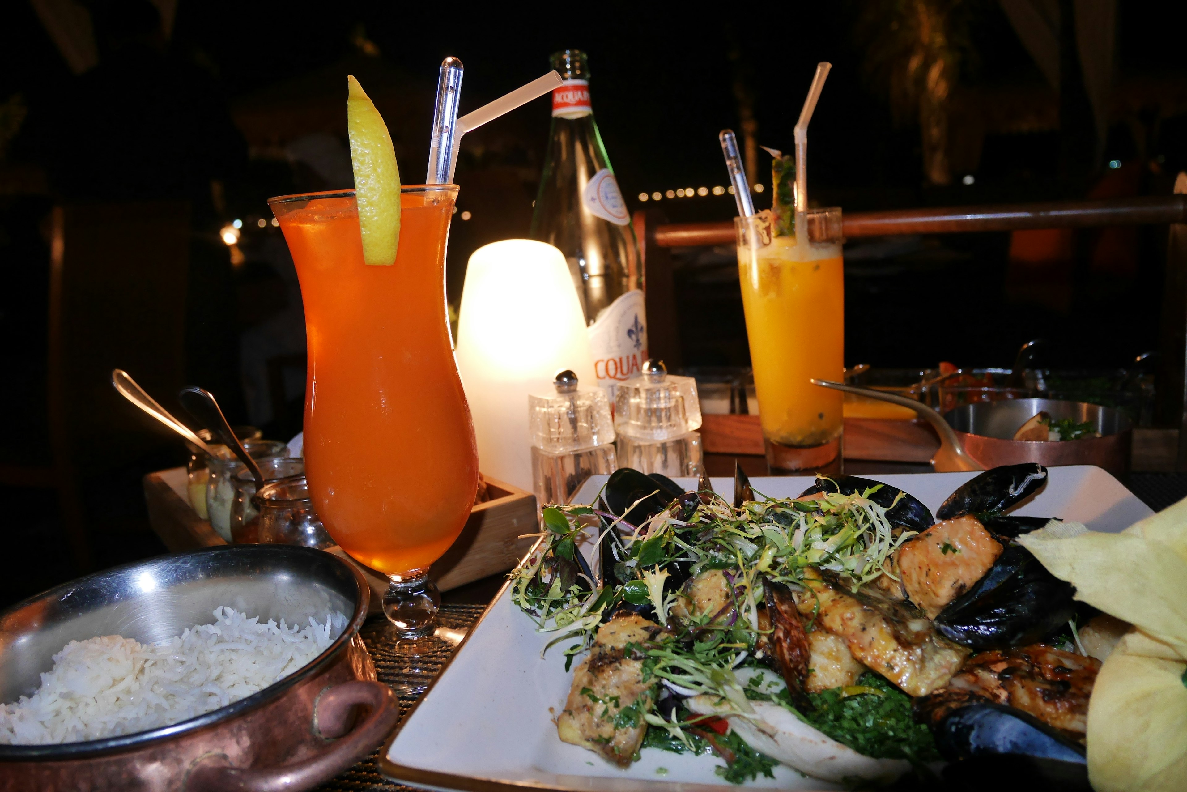 A table scene featuring vibrant cocktails and a seafood platter