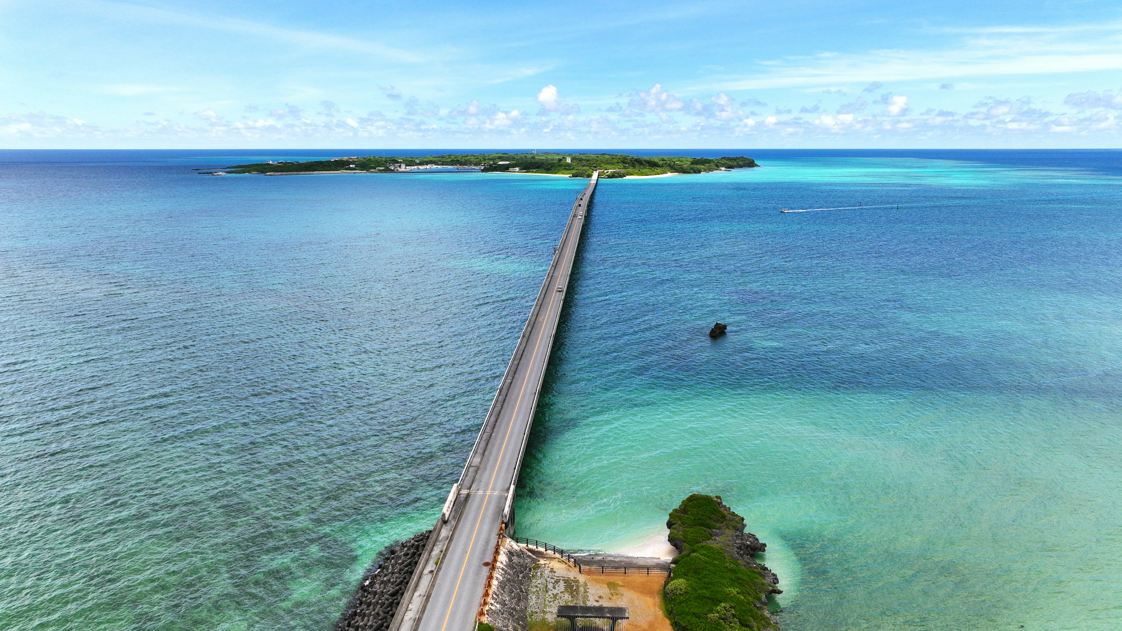 Pemandangan jembatan yang membentang di atas air biru menuju sebuah pulau