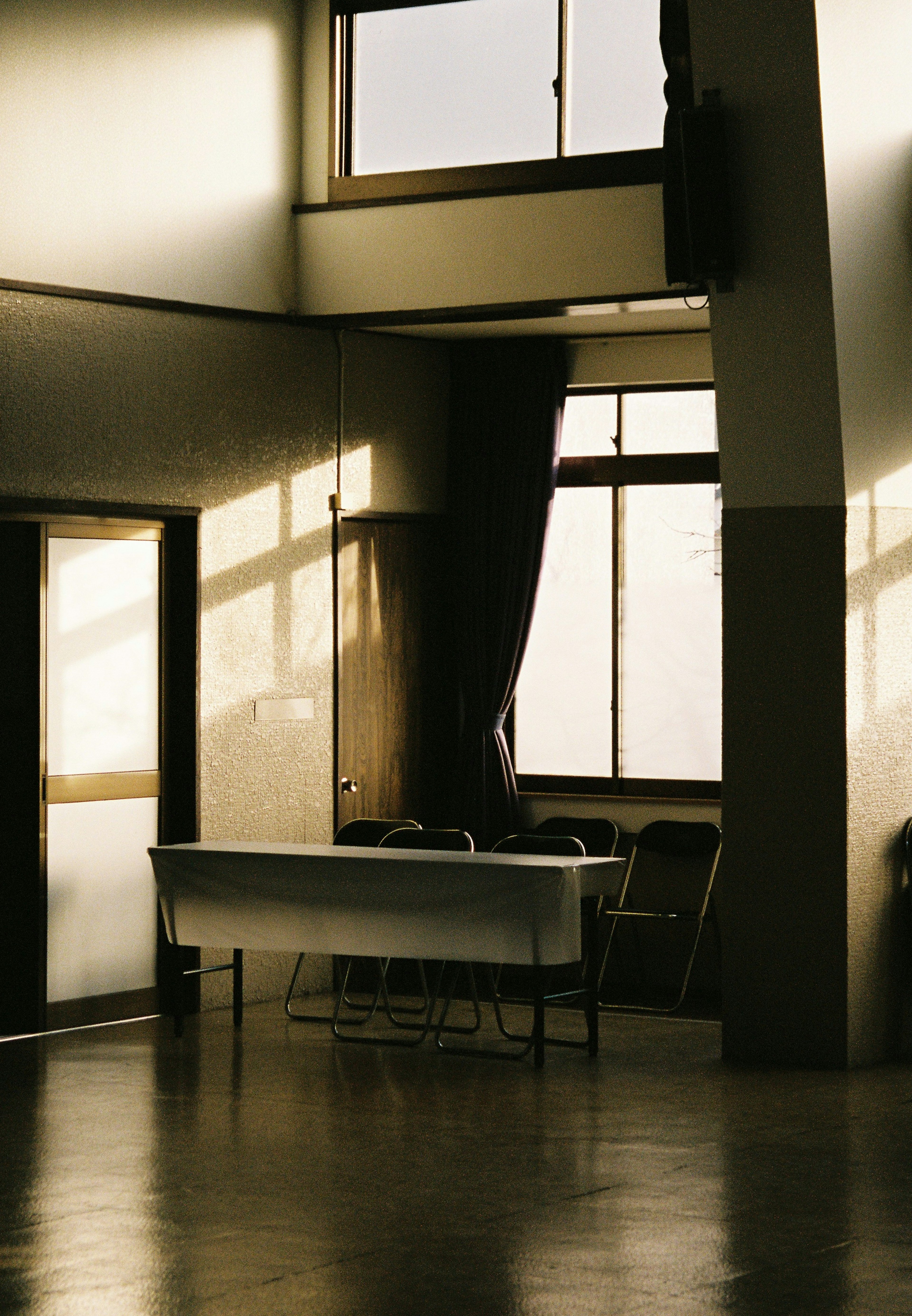 A simple room featuring a white table and chairs illuminated by bright windows