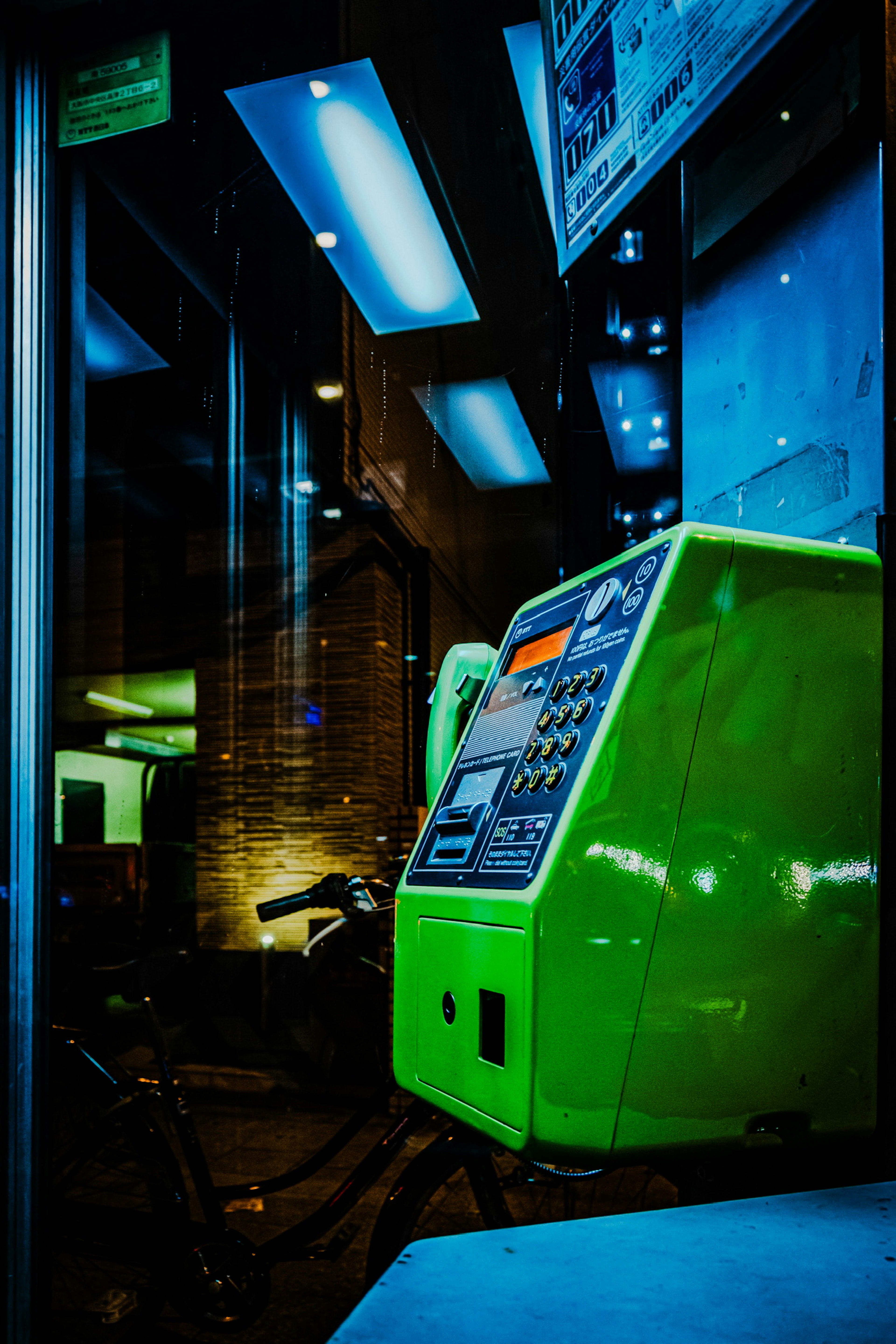 A green vending machine illuminated in a nighttime urban setting