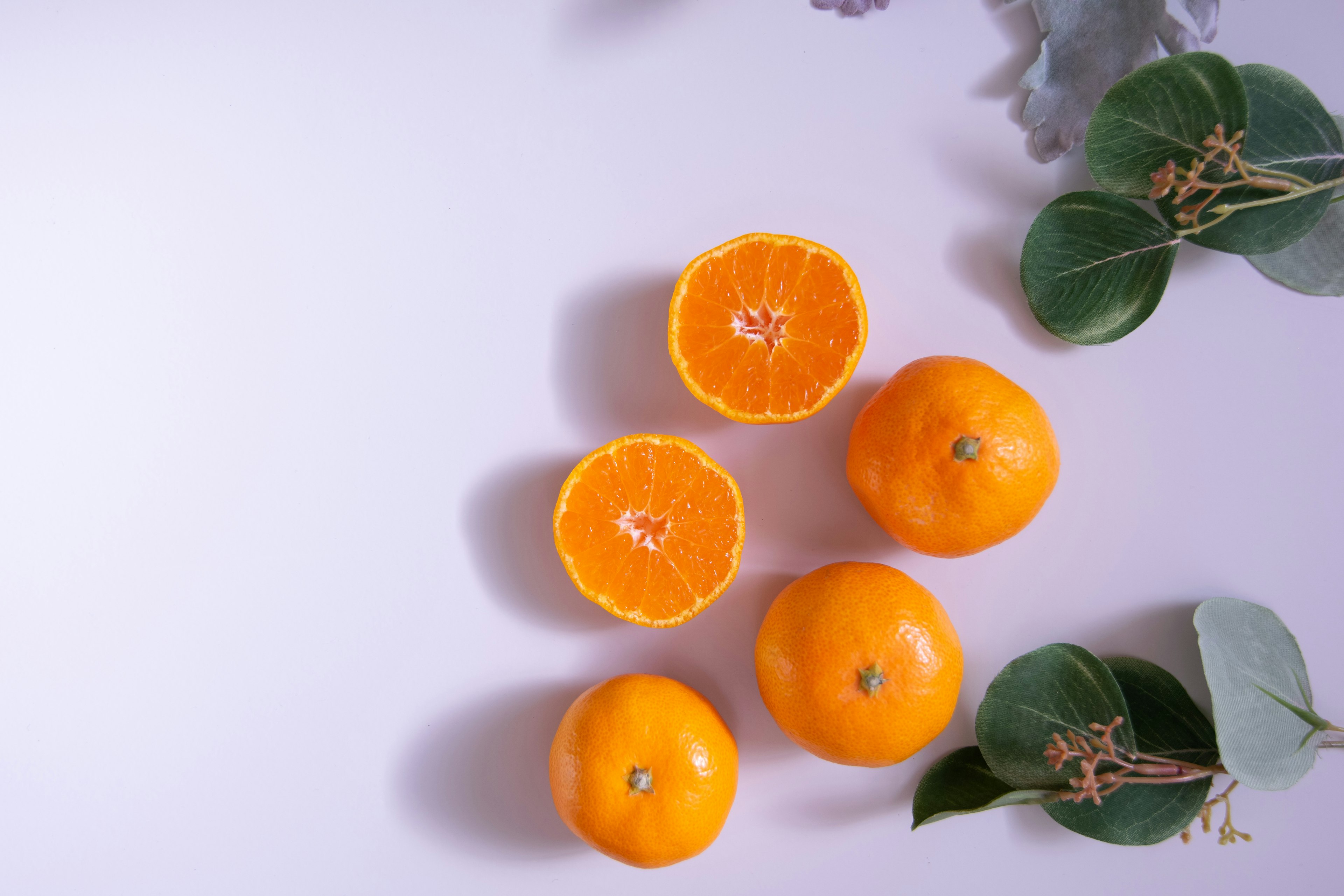 Image d'oranges disposées avec une orange coupée en deux et des feuilles vertes