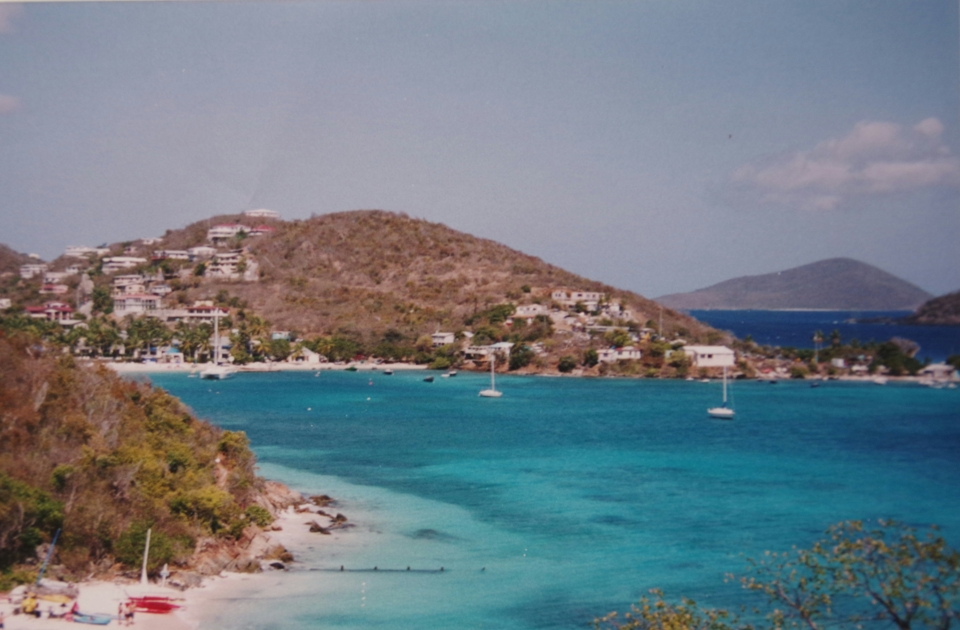 Vista panoramica di una spiaggia con acqua turchese e colline verdi