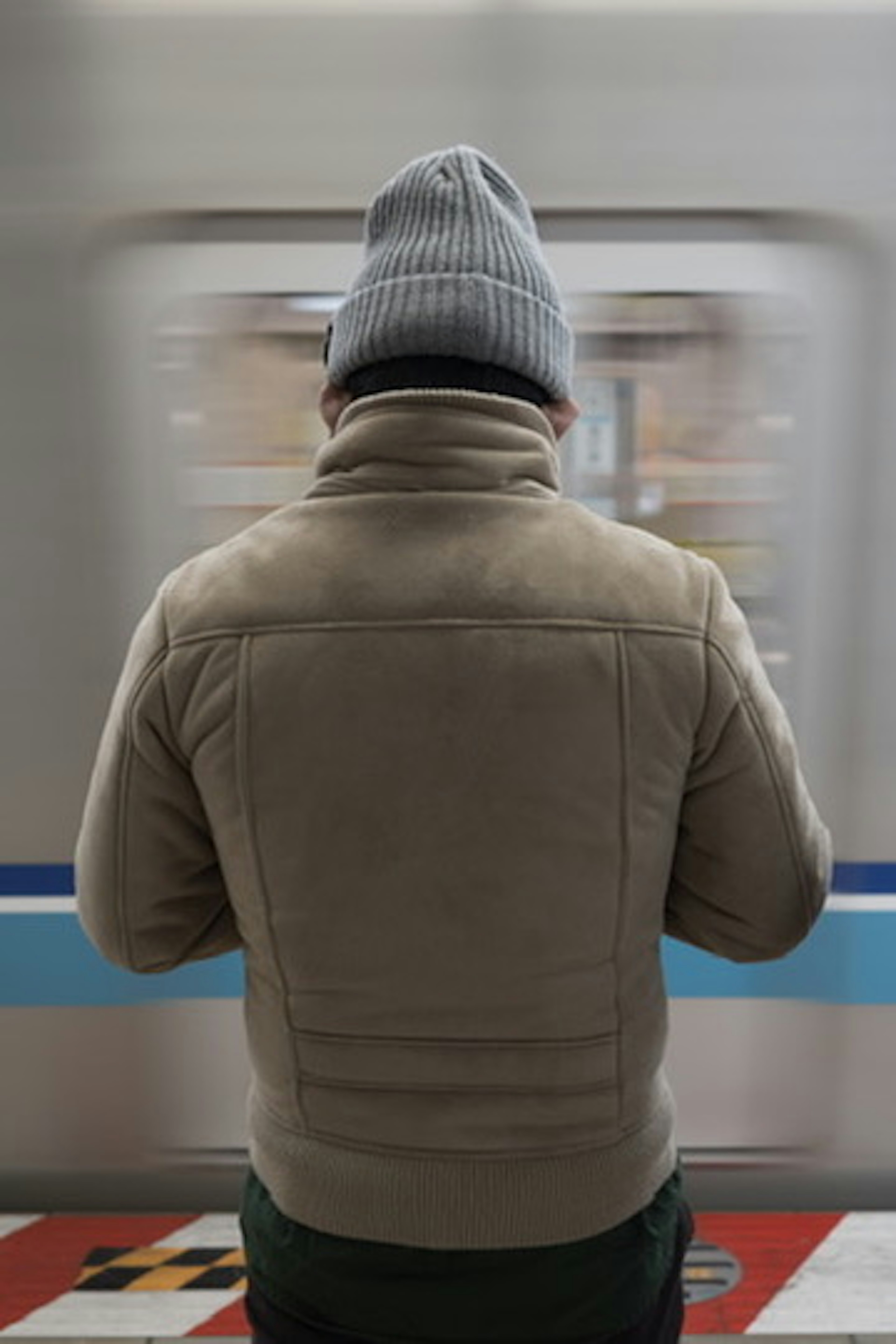 Un hombre esperando un tren visto desde atrás Ropa de invierno Gorro de lana gris