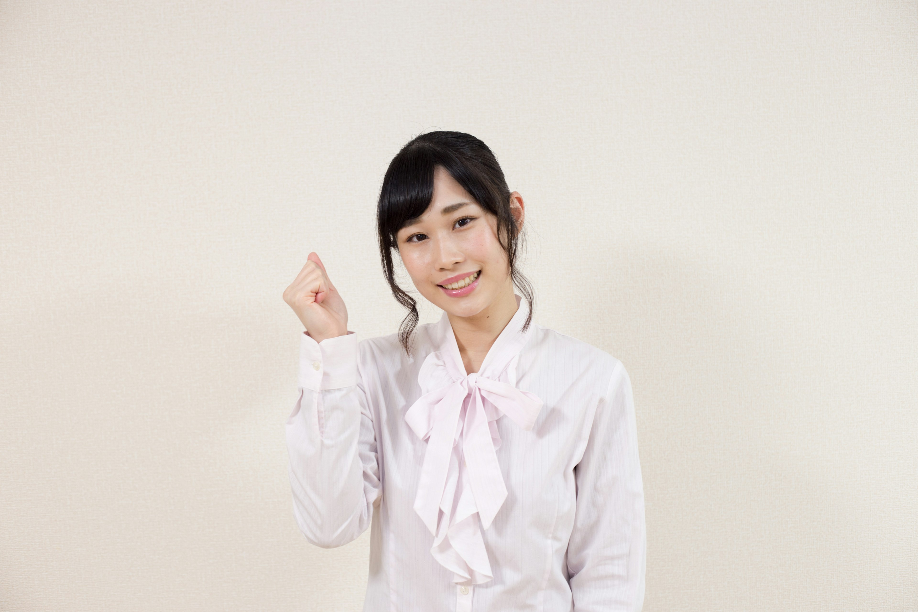 A woman in a white blouse smiling and raising her hand