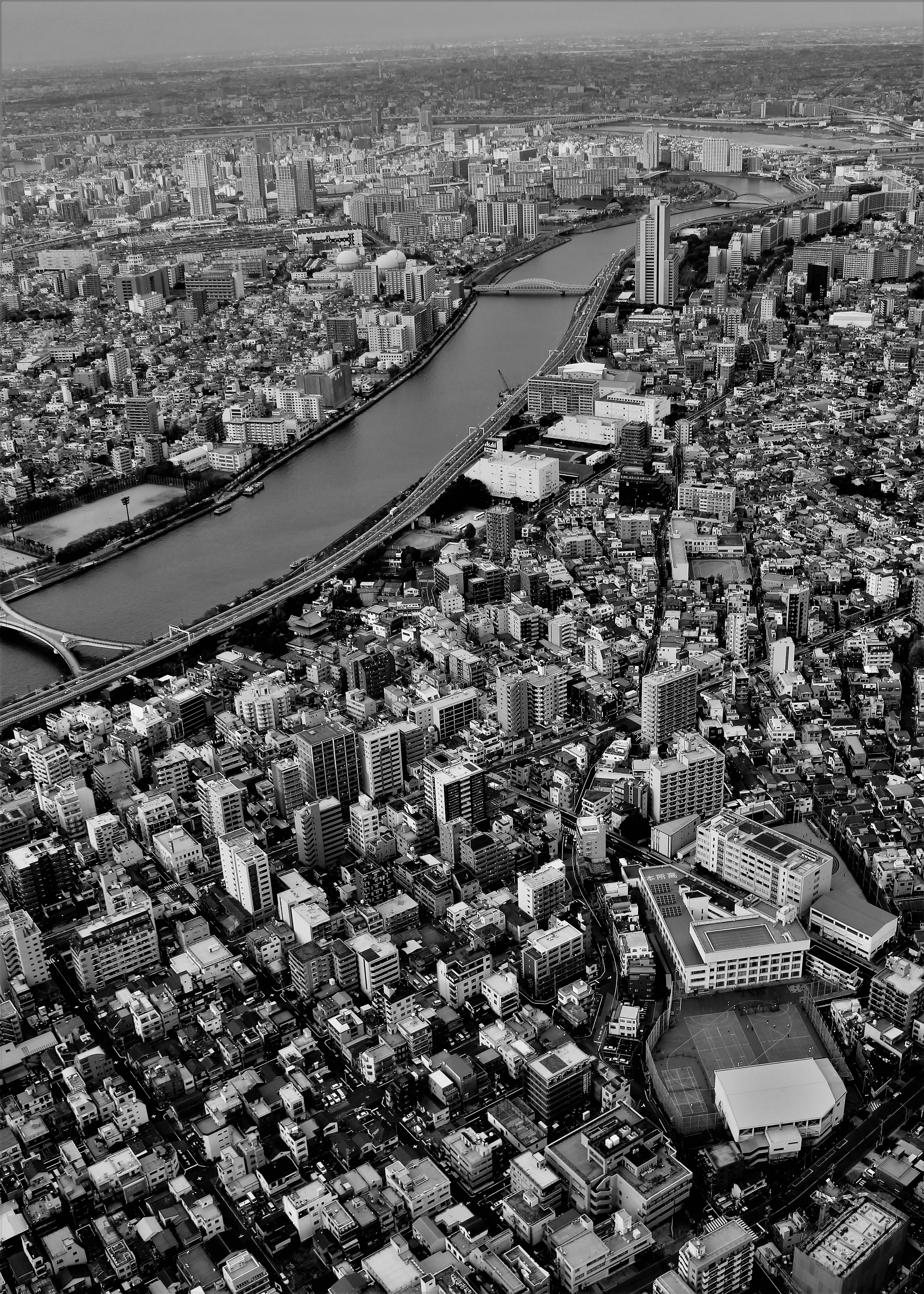 東京の上空からの白黒写真ビルと川が見える