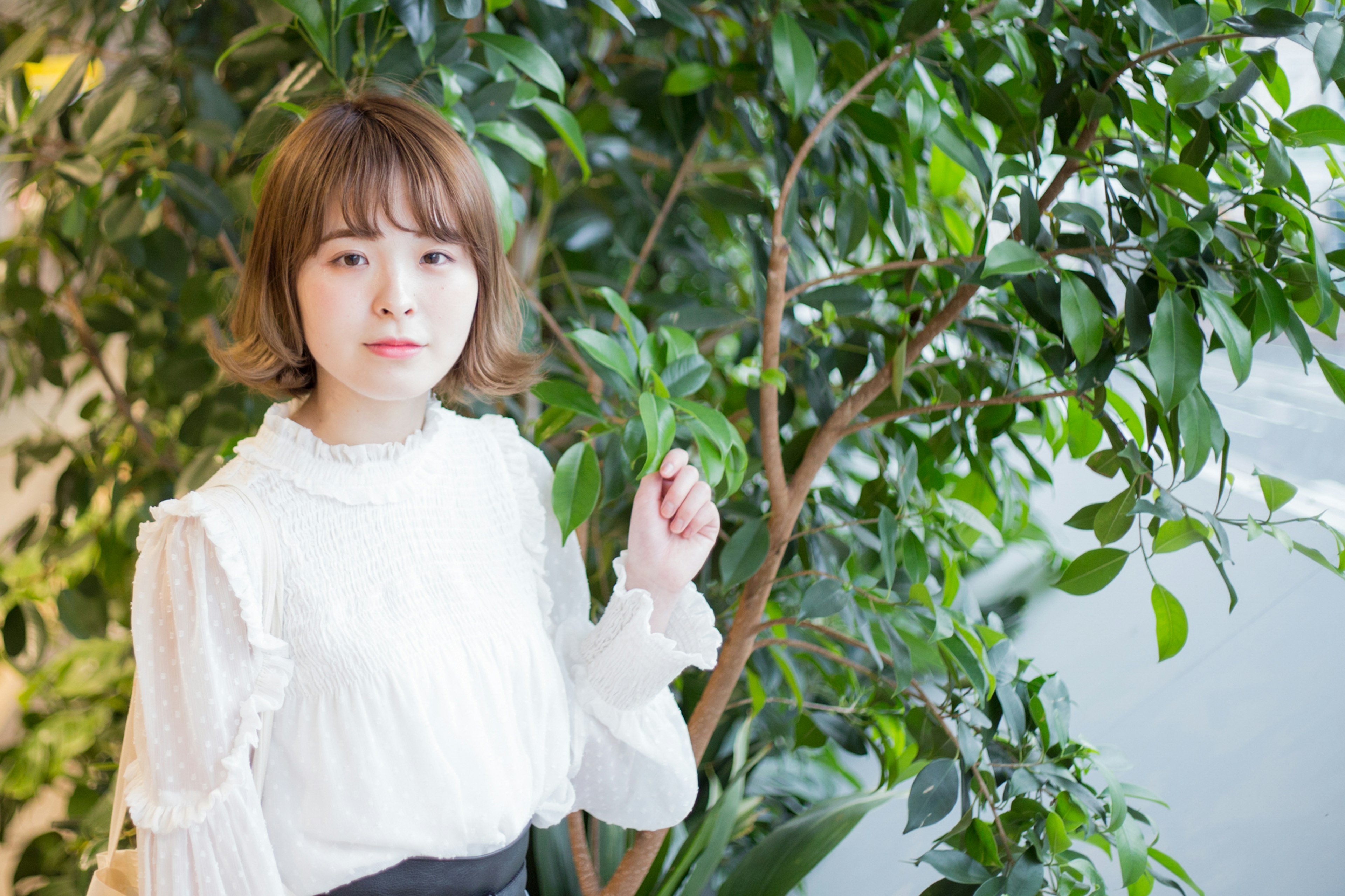 Young woman posing in front of green plants