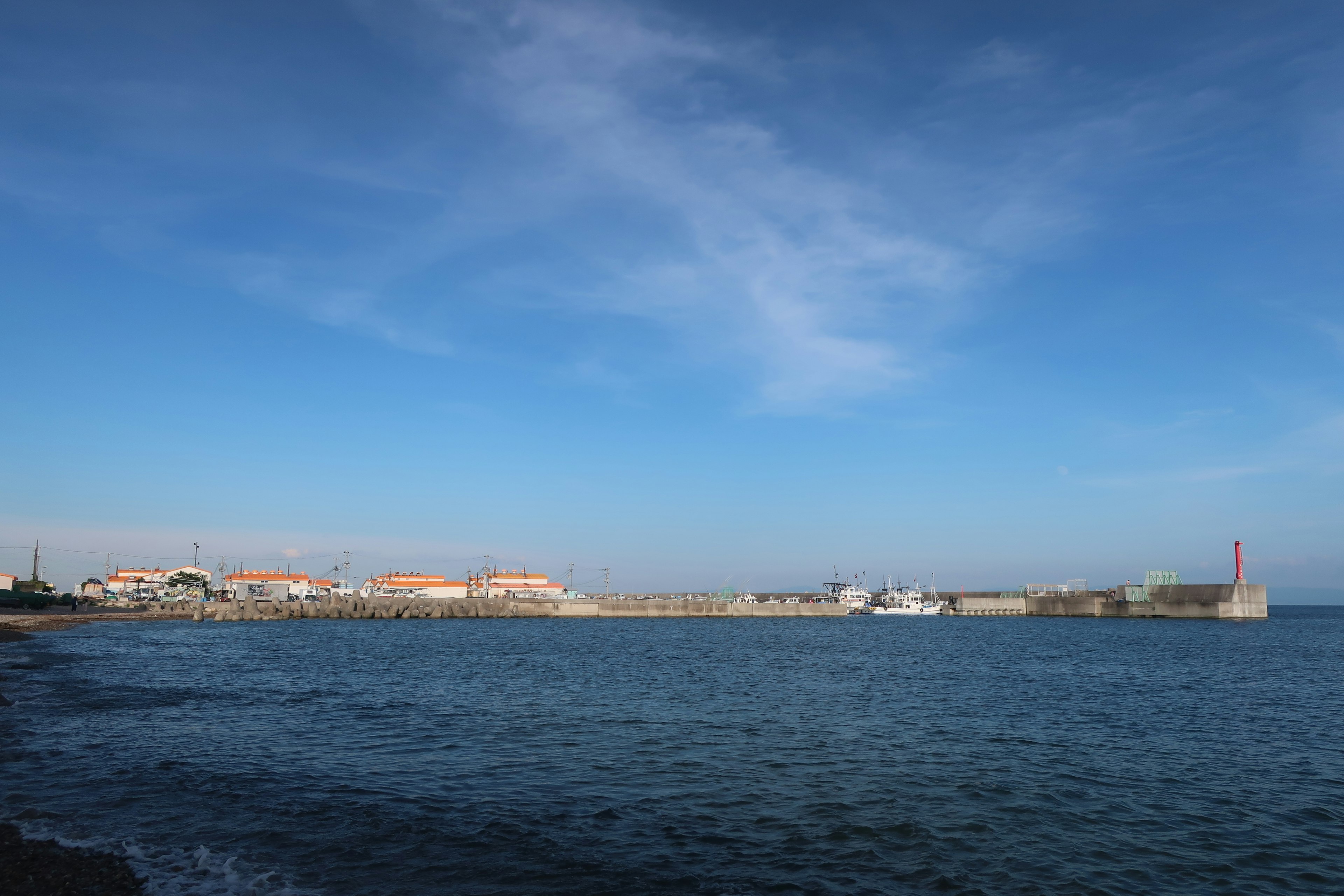 Hafenansicht umgeben von blauem Himmel und Meer mit Booten und Ufer