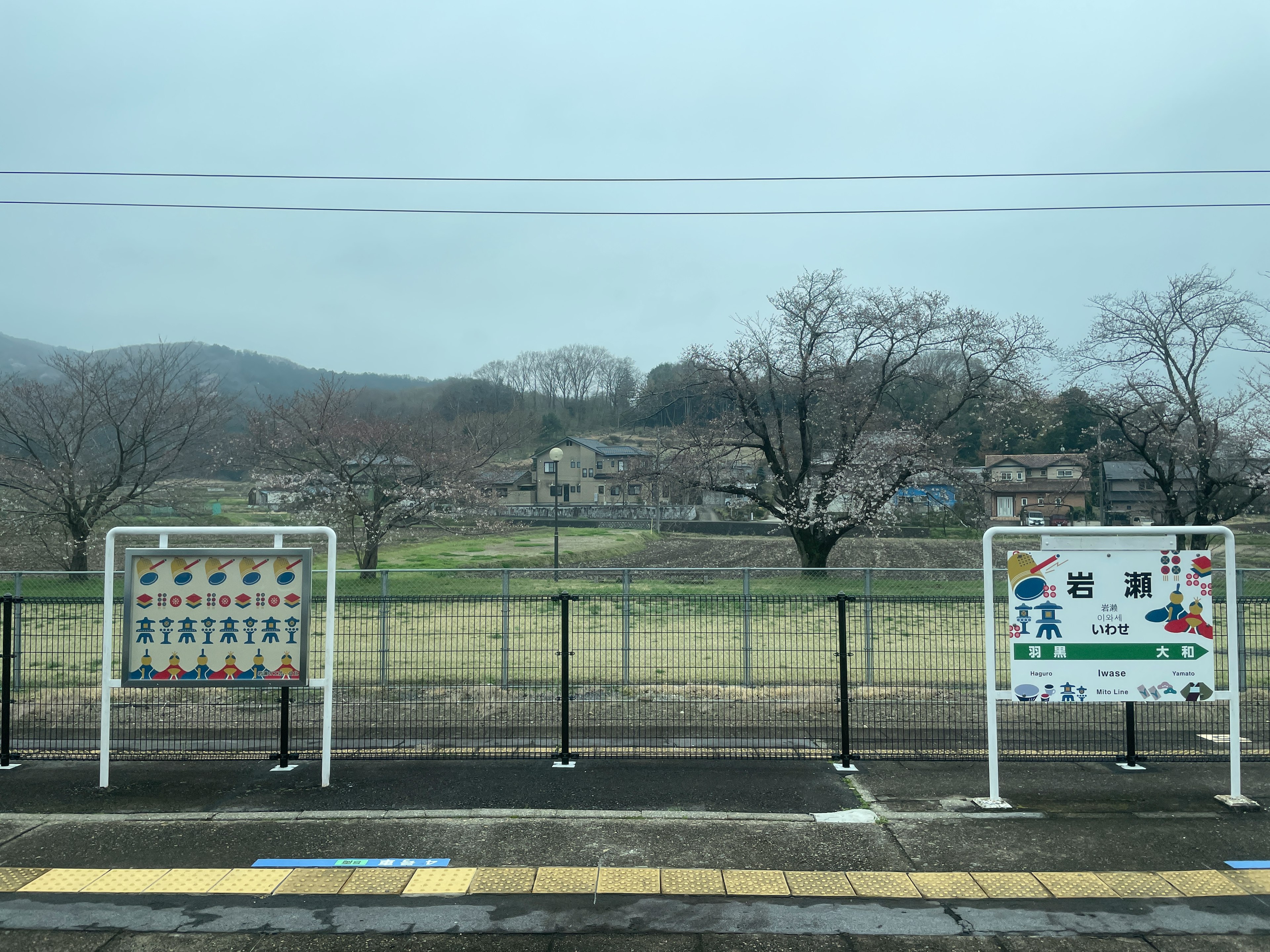 曇りの日に駅のホームから見える風景と案内板