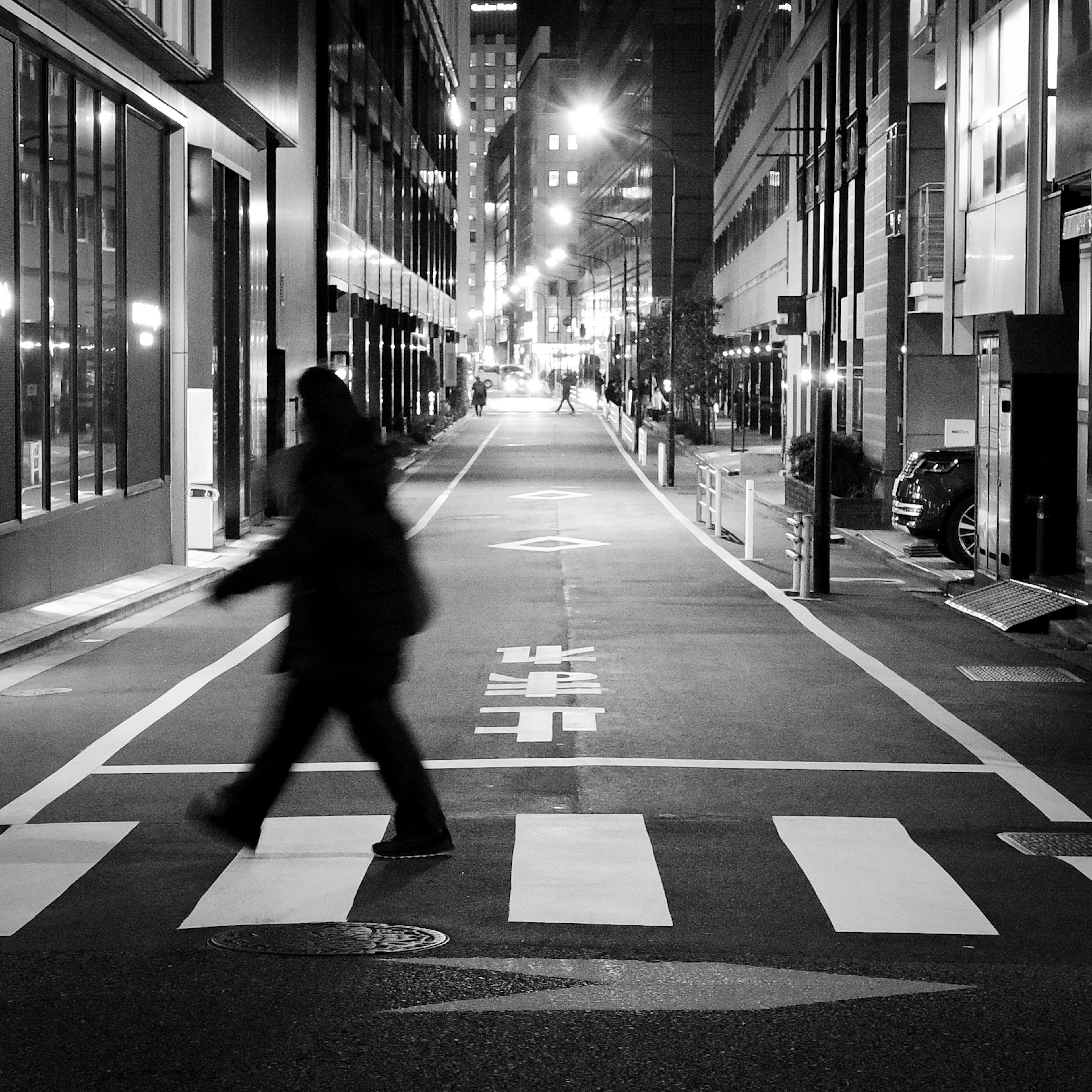 Siluet seseorang menyeberang jalan di lingkungan perkotaan malam