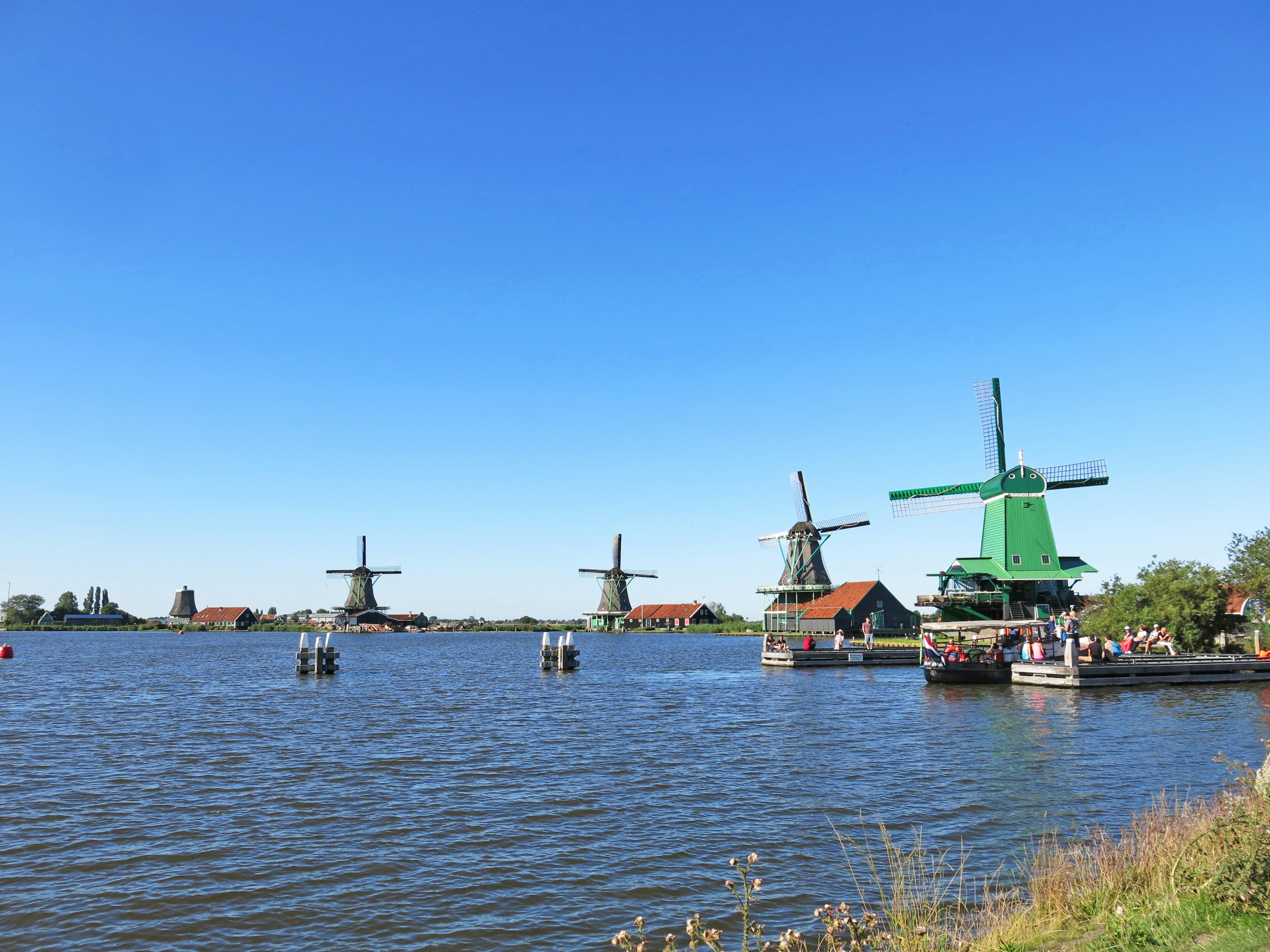 Scenic view of windmills by the water under a clear blue sky