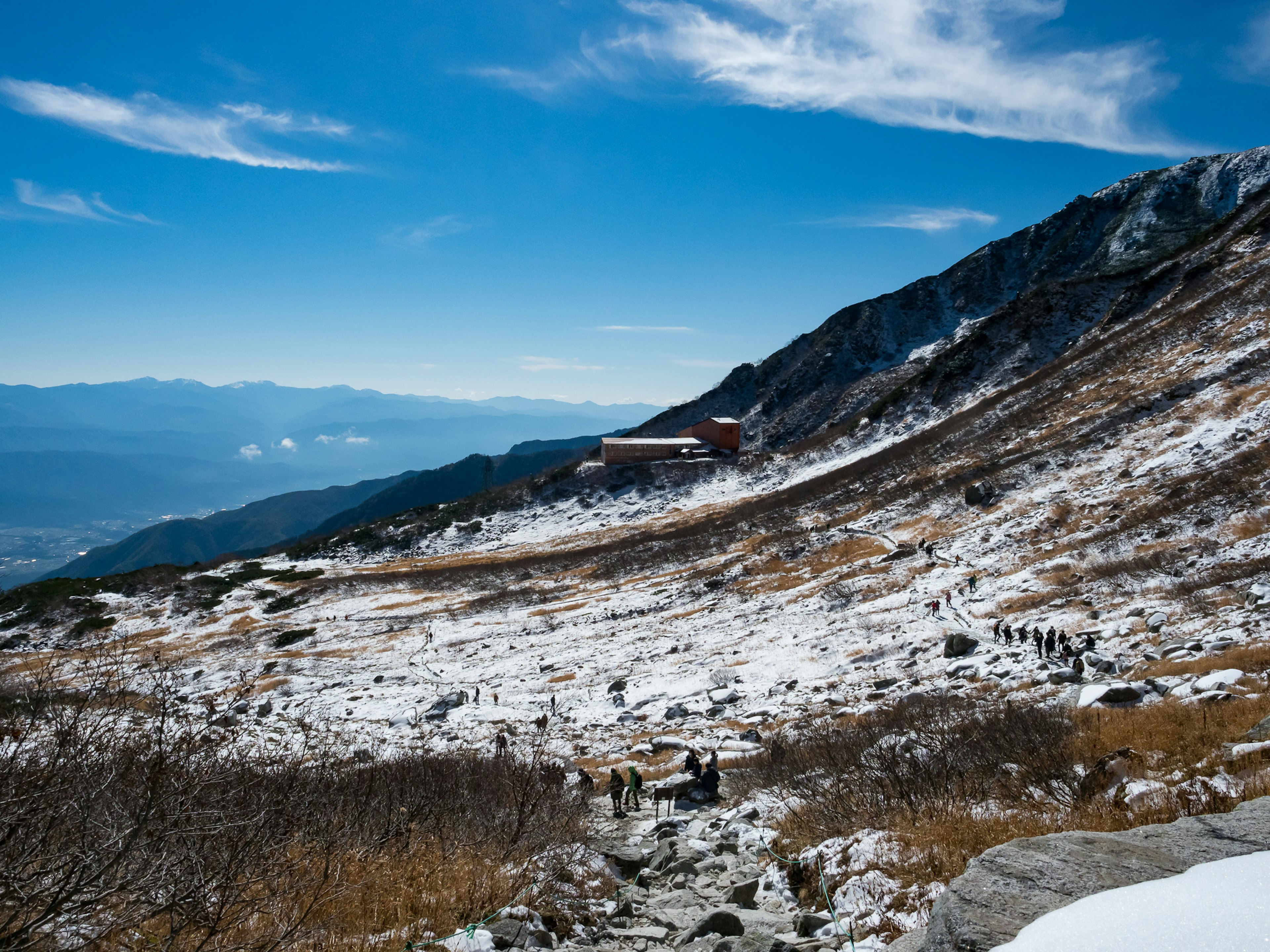 Schneebedeckter Berghang mit einem Gebäude unter einem blauen Himmel