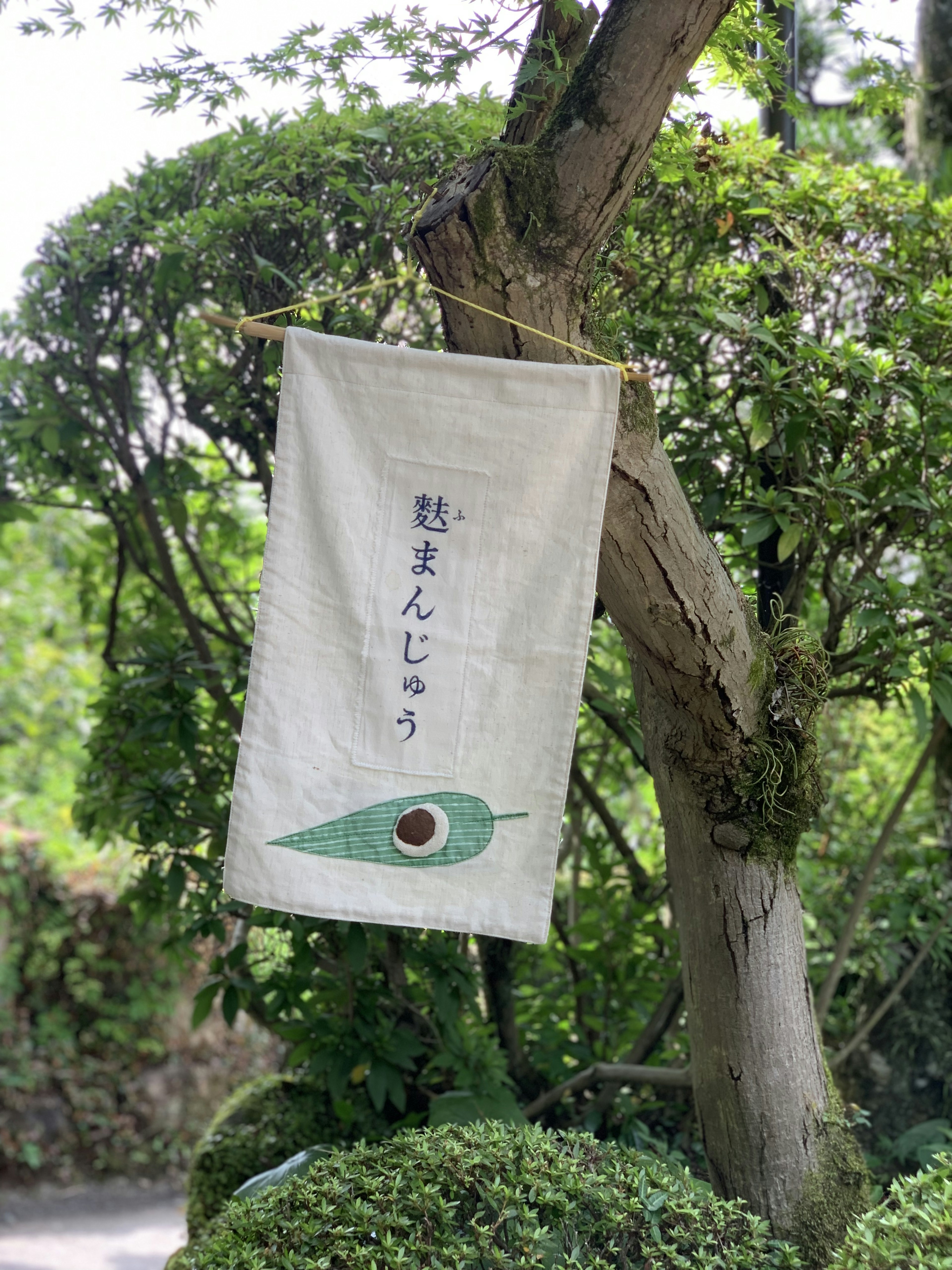 Japanese flag with a green leaf design hanging from a tree