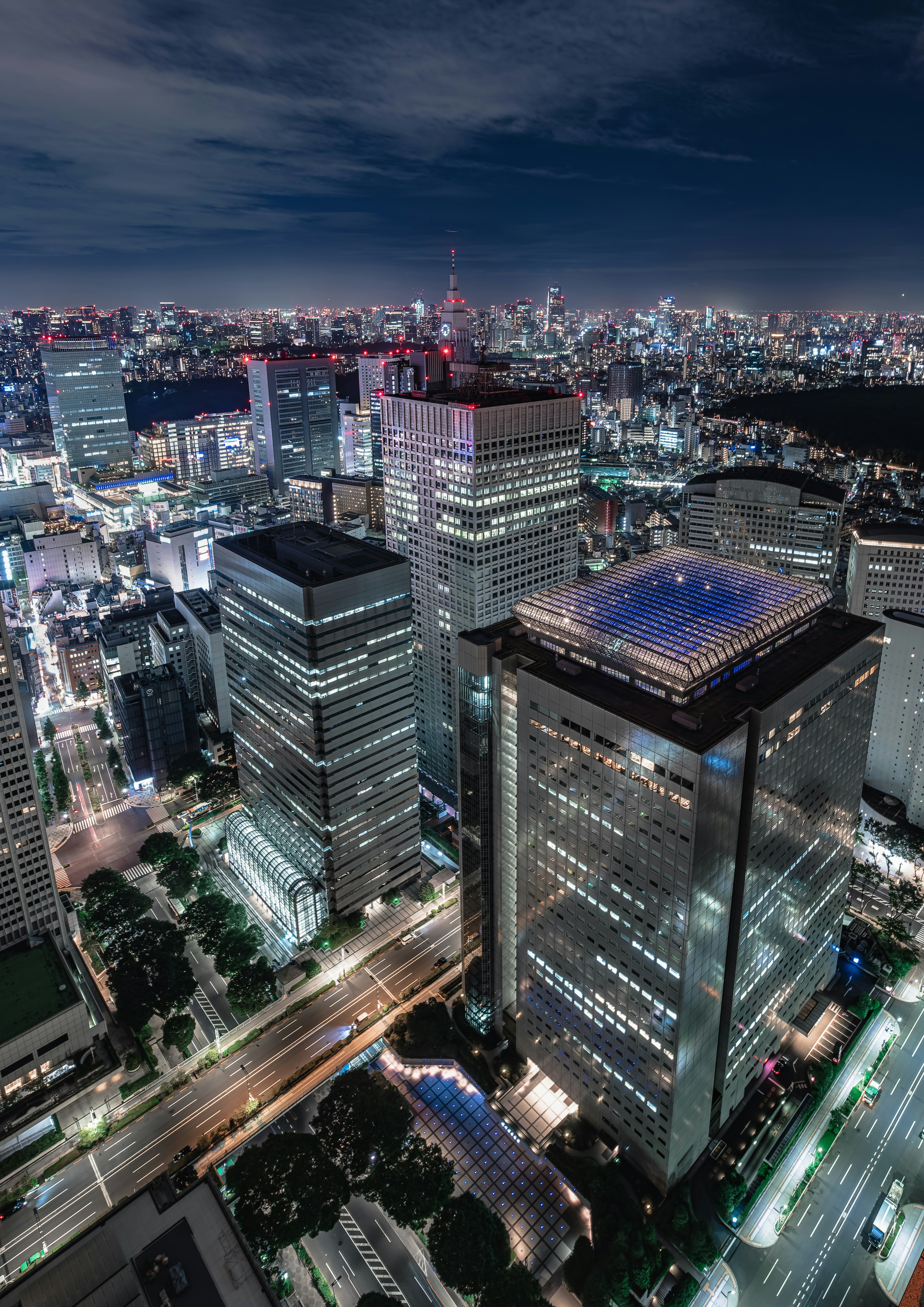 Pemandangan kota Tokyo di malam hari dengan gedung pencakar langit dan jalan yang diterangi