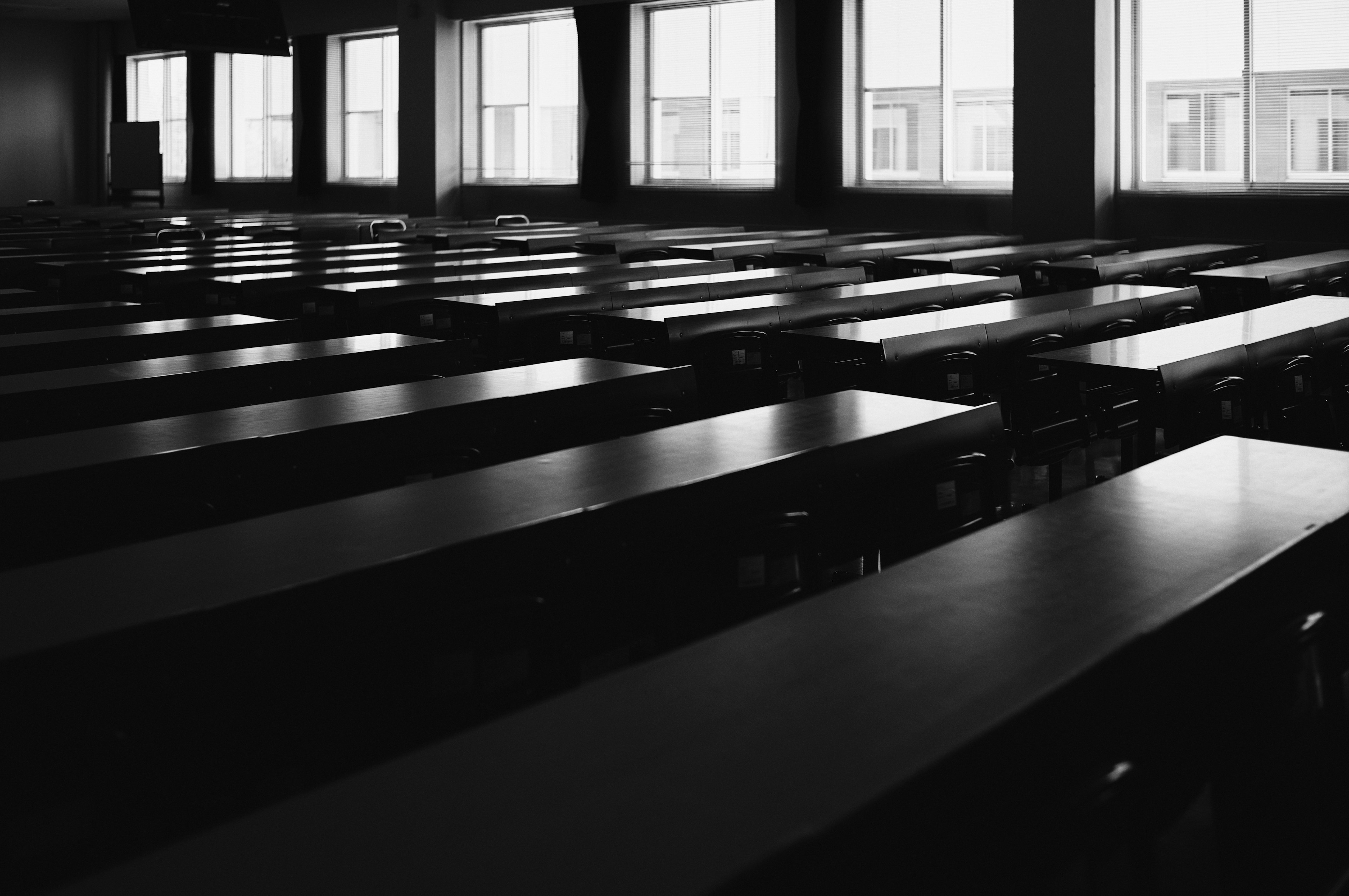 Intérieur d'une salle de classe en noir et blanc grandes fenêtres laissant entrer la lumière naturelle tables disposées de manière ordonnée