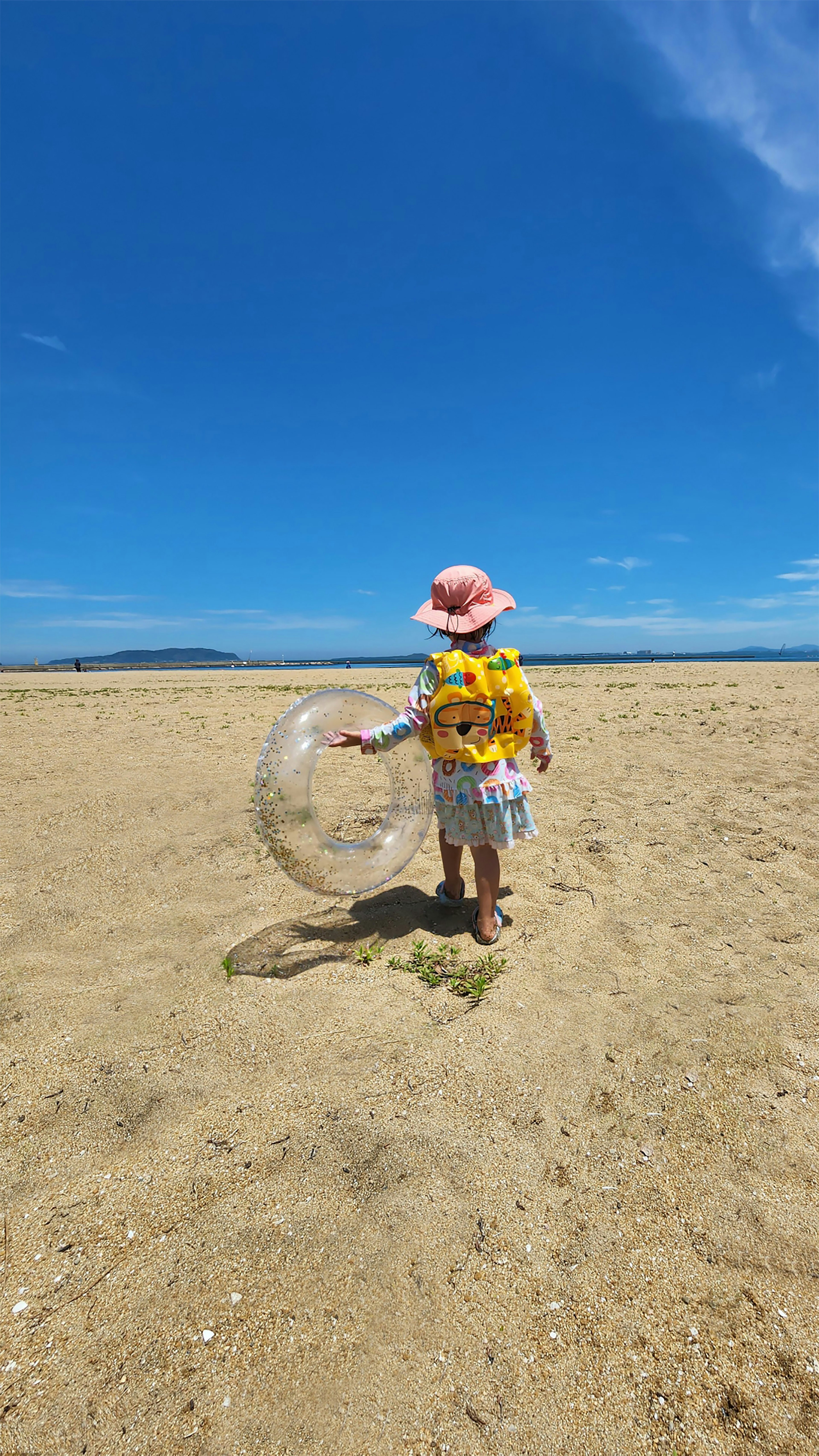 Bambino che gioca con le bolle su una spiaggia di sabbia sotto un cielo azzurro