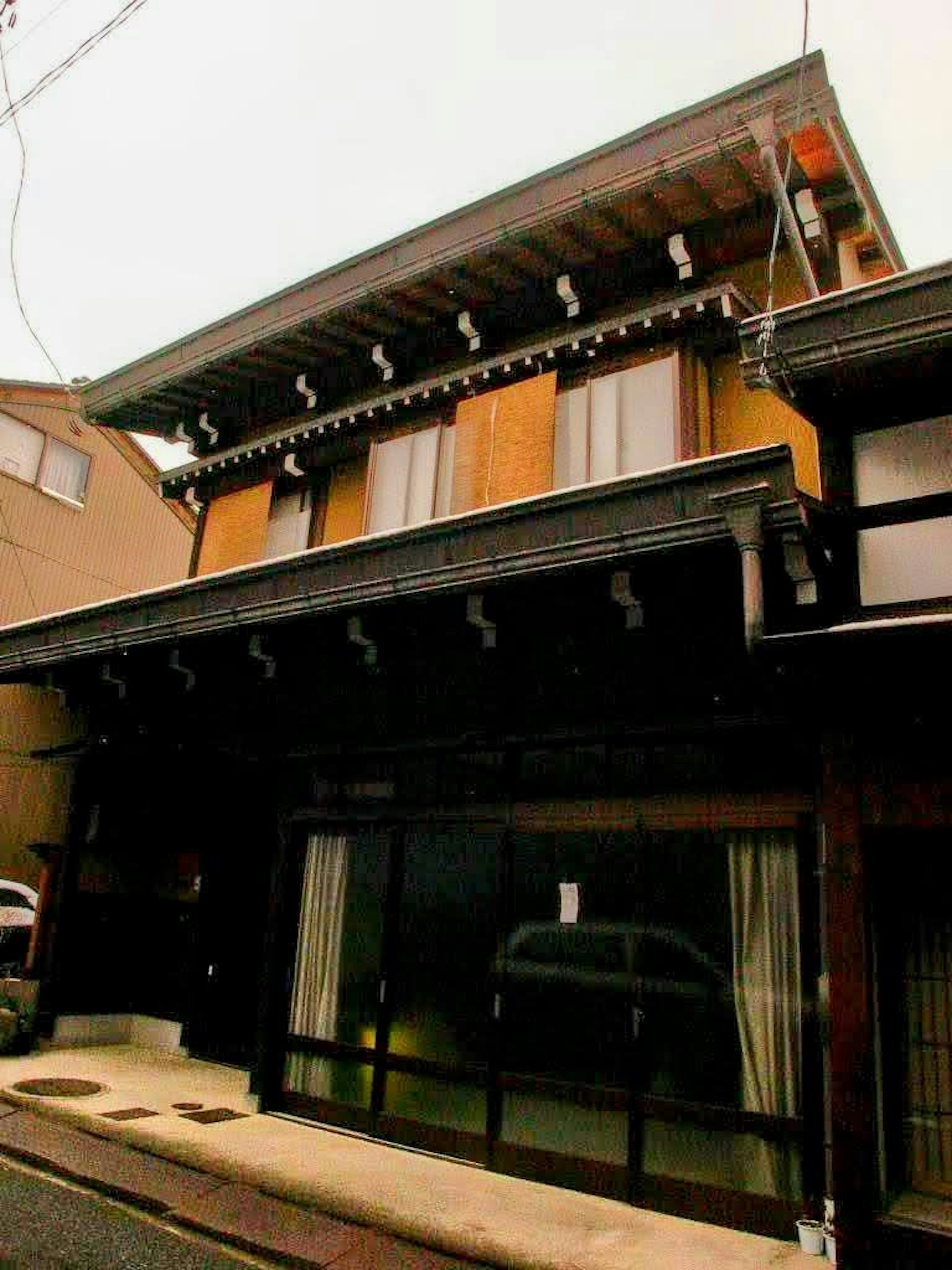 Außenansicht eines traditionellen japanischen Hauses Zweigeschossige Holzkonstruktion Großes Eingangsfenster und Dachdesign