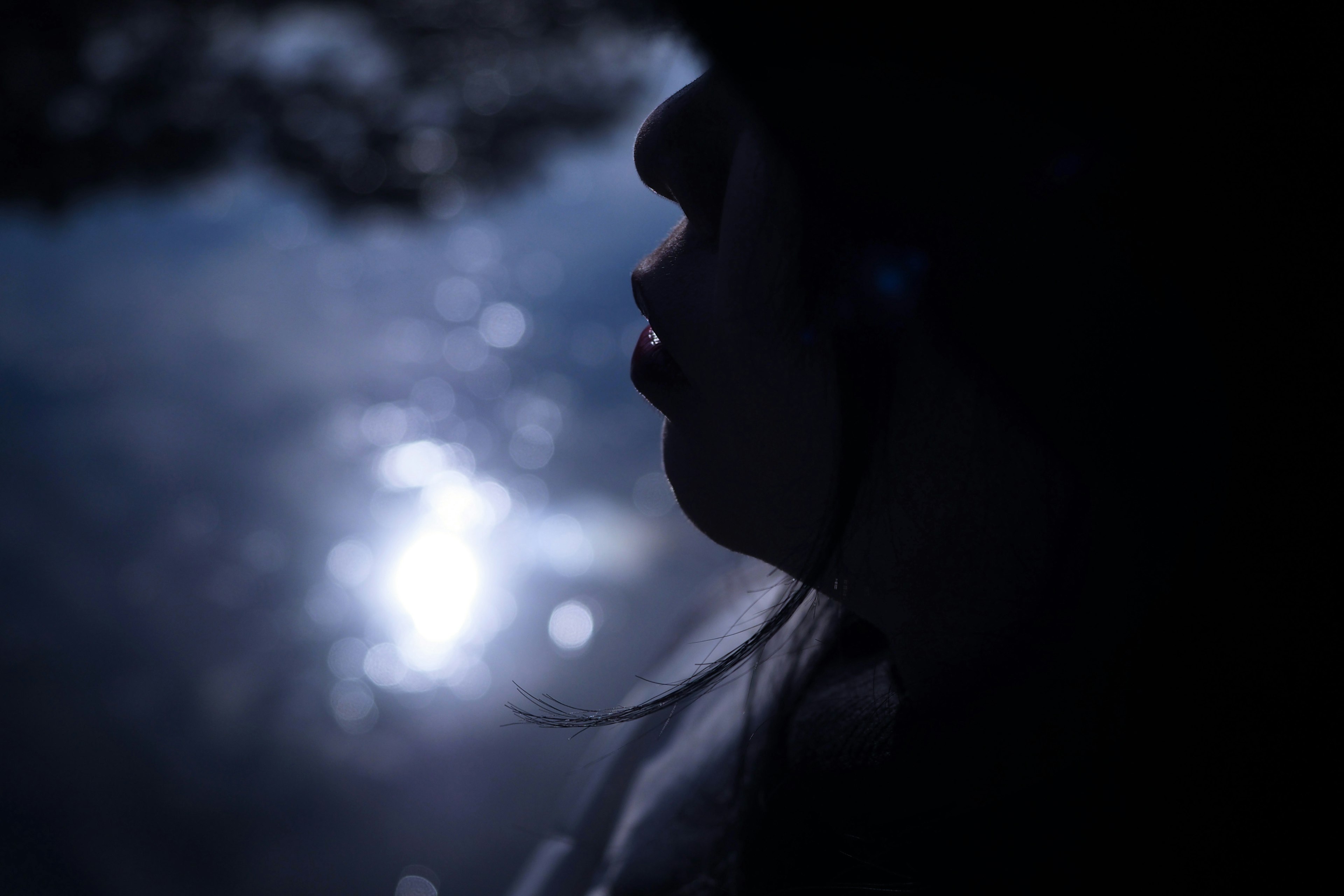 Silhouette einer Frau vor dem Licht, das sich auf dem Wasser spiegelt