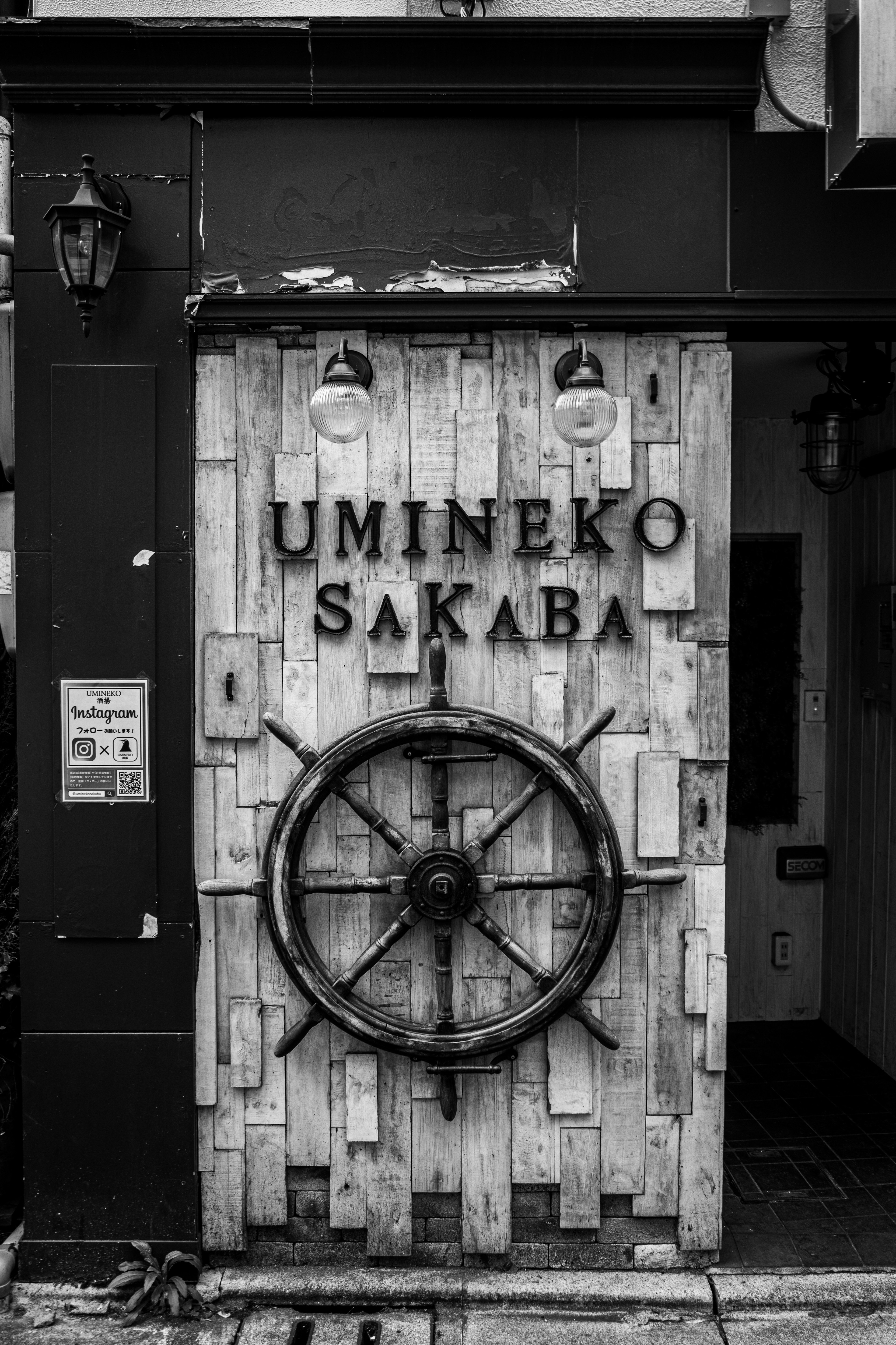 Puerta de madera de Umineko Sakaba con una rueda de barco decorativa