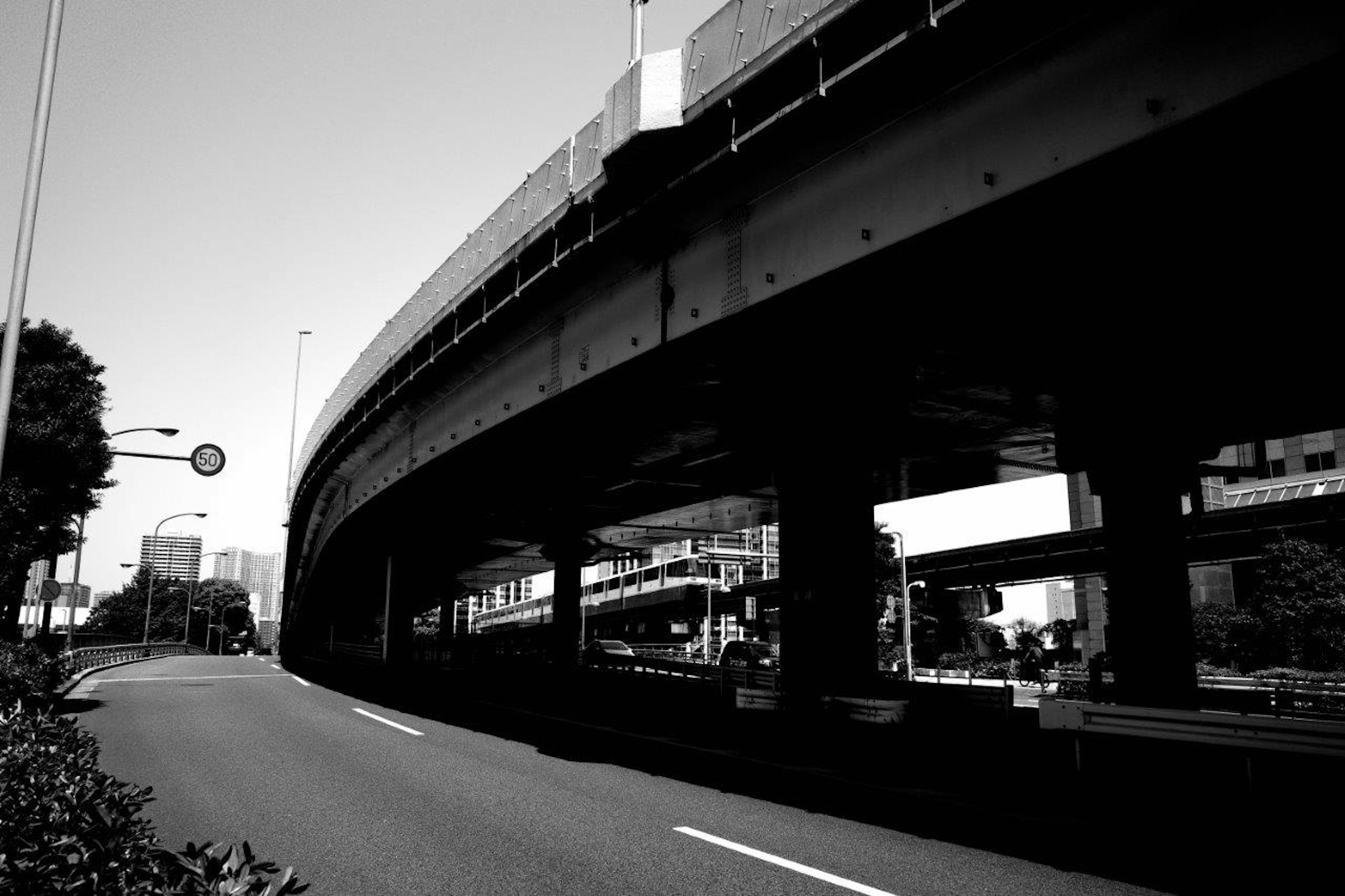 黒白の高速道路の下の風景 車道と建物が見える