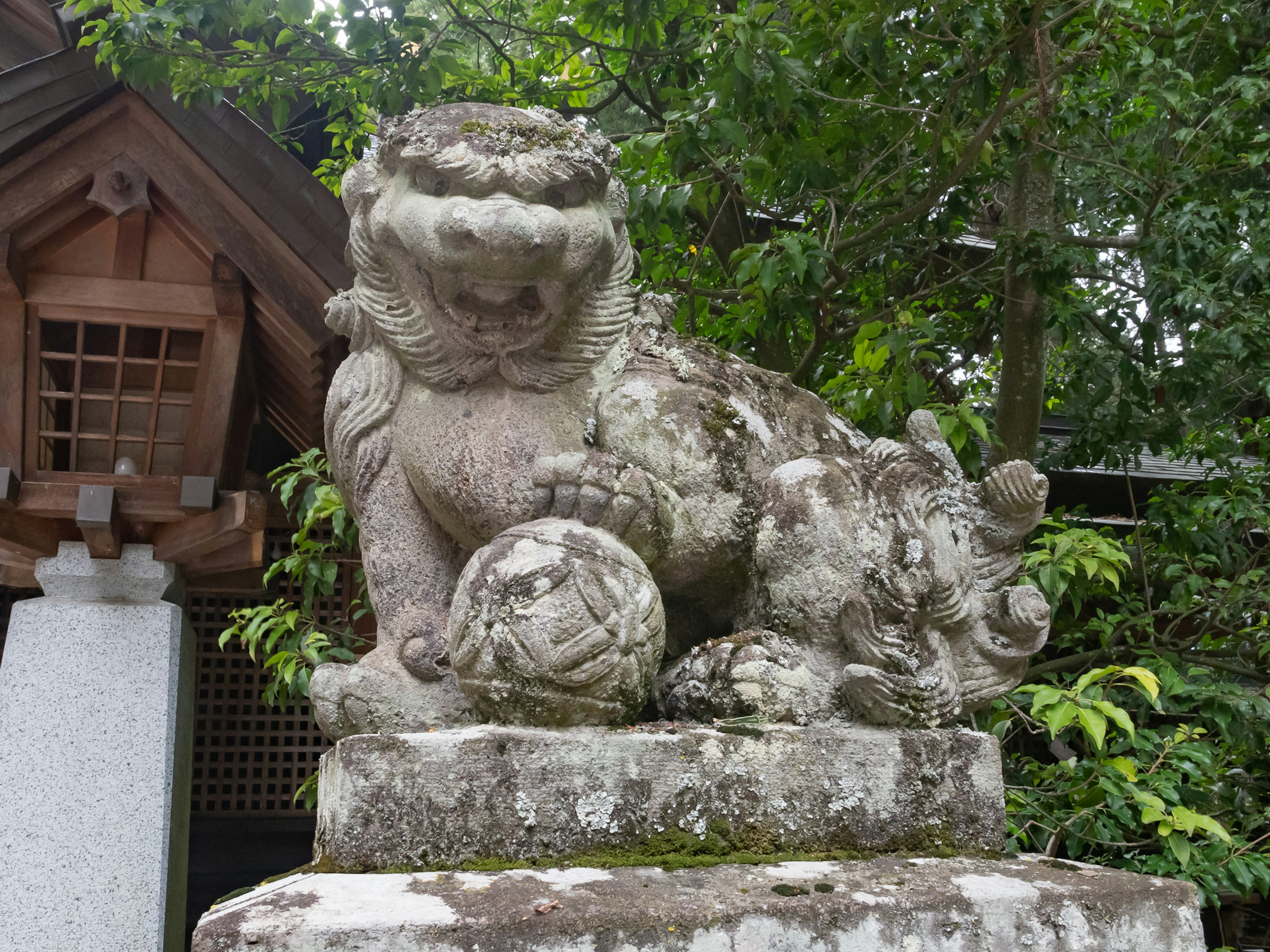 Estatua de león de piedra sentada entre árboles verdes