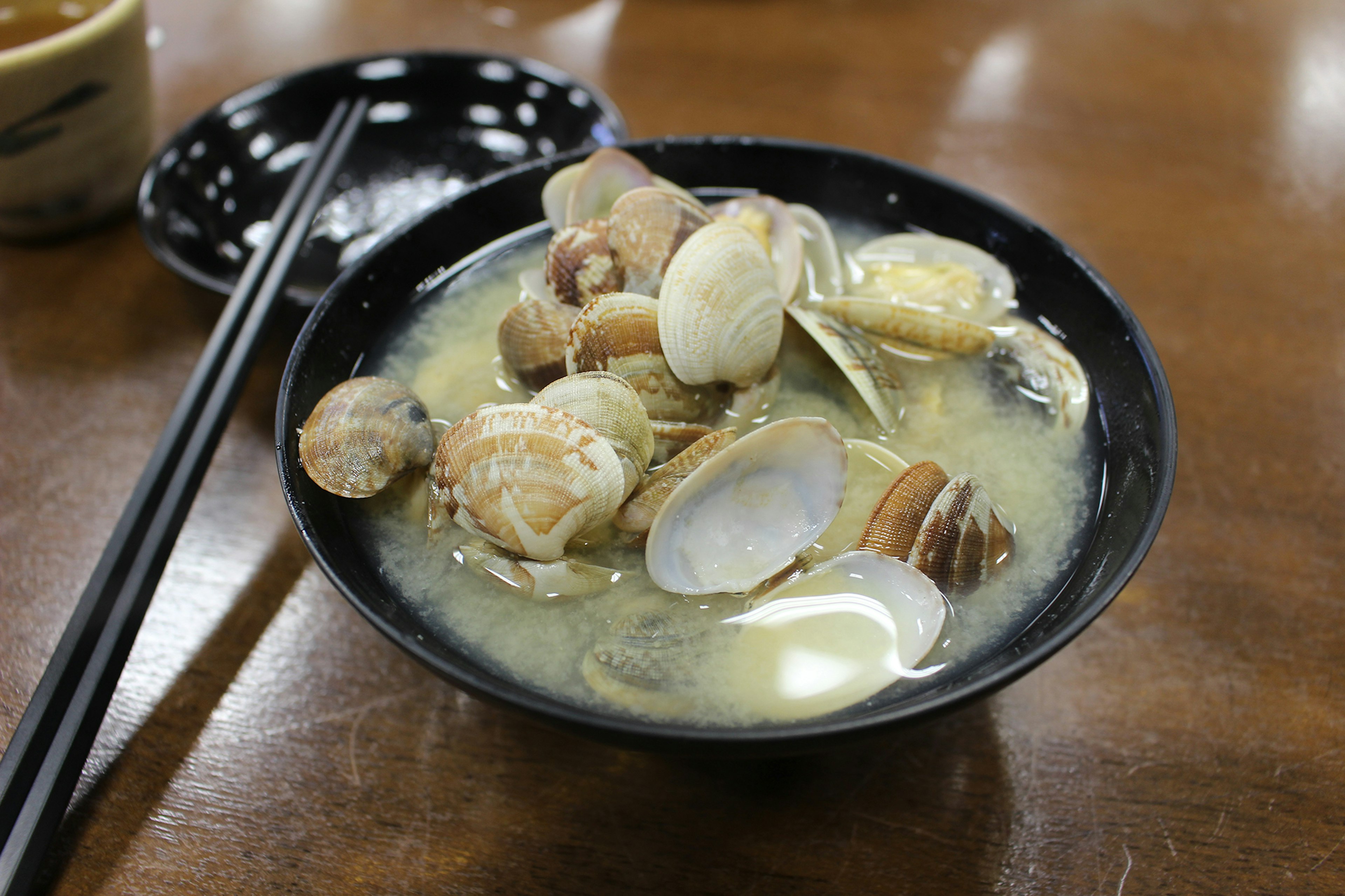 Tazón de sopa de almejas con varias almejas y palillos