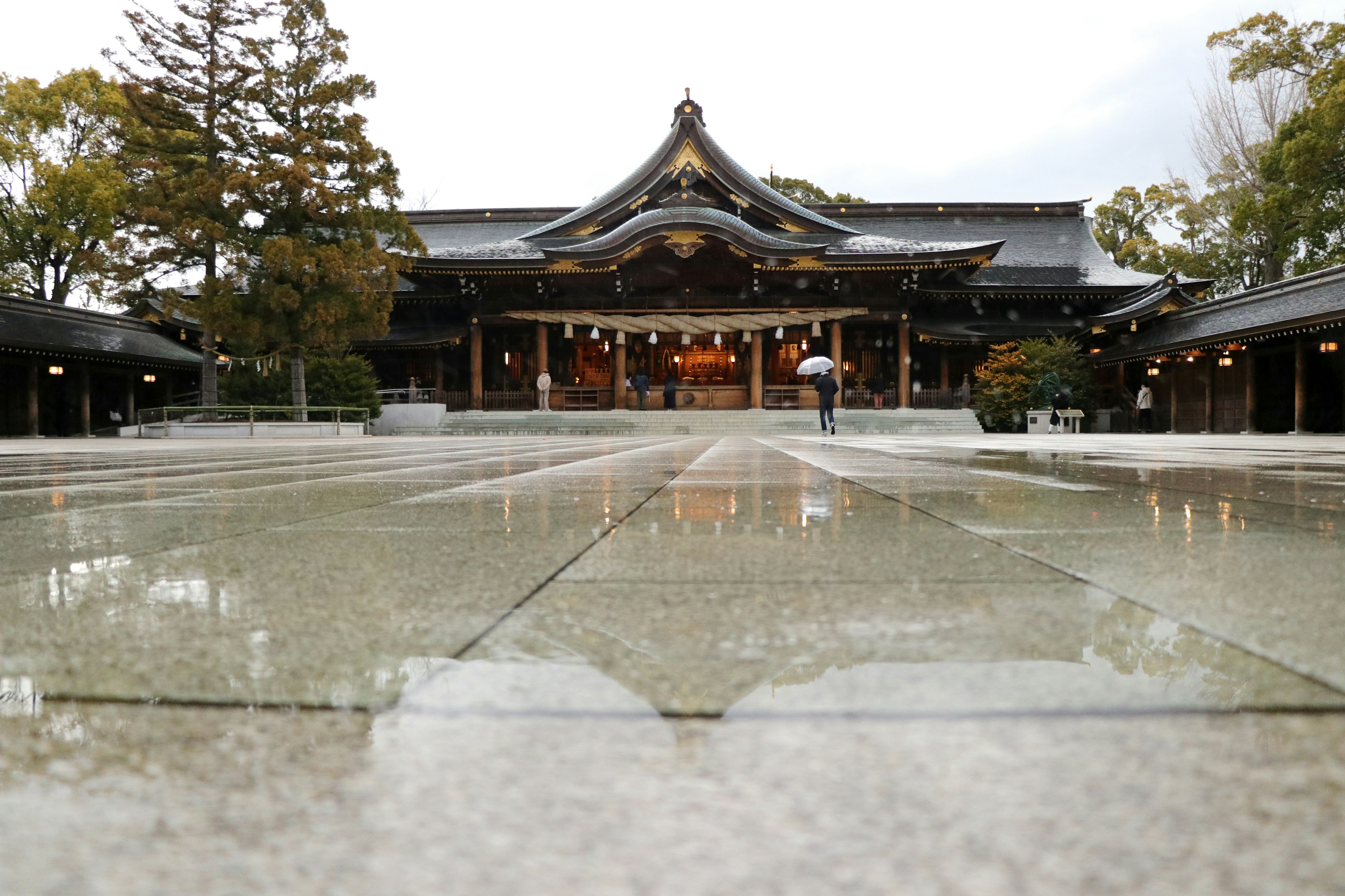 Traditional shrine building in the background with wet stone pavement in the foreground