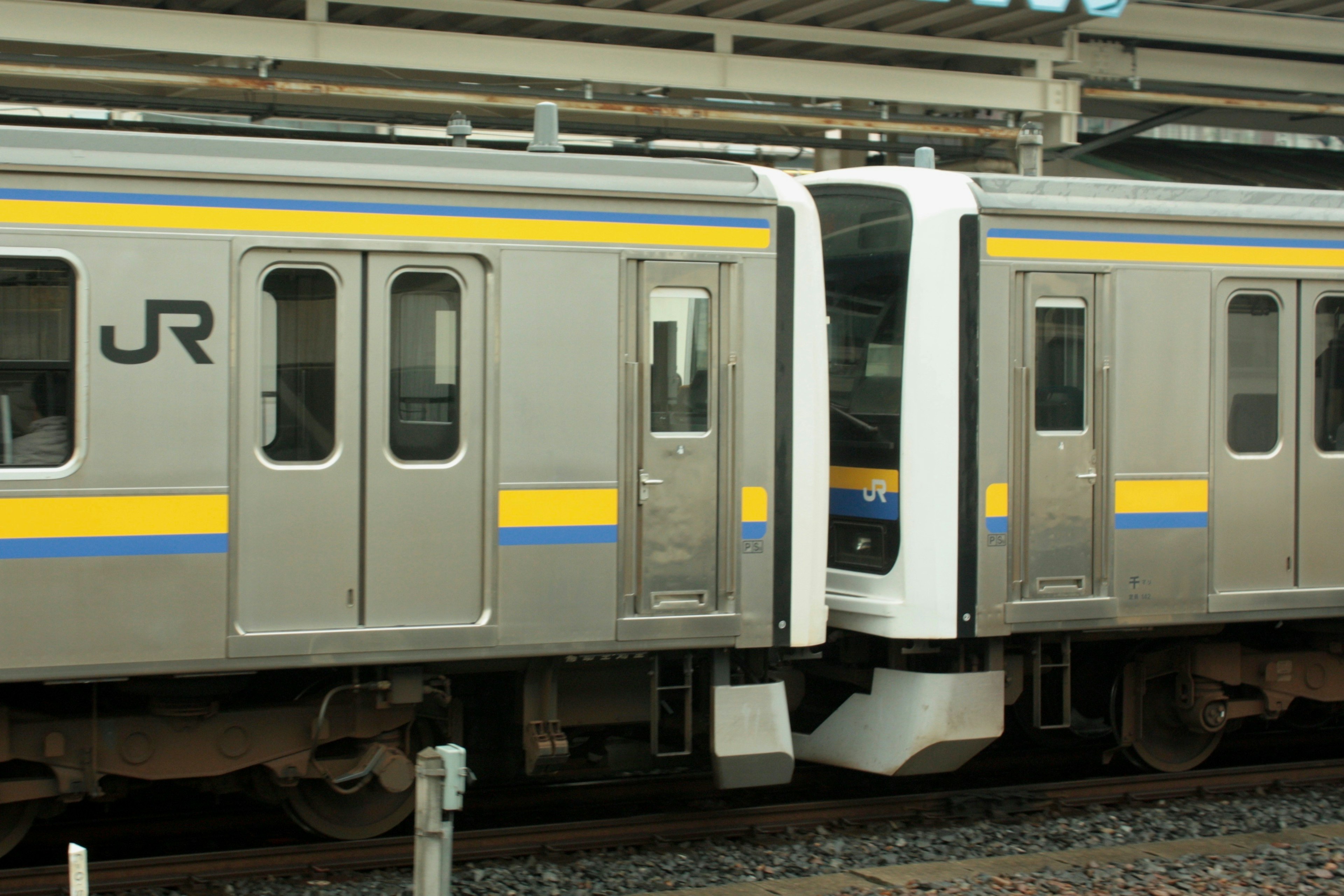 Primer plano de la conexión de un tren JR con diseño plateado y azul