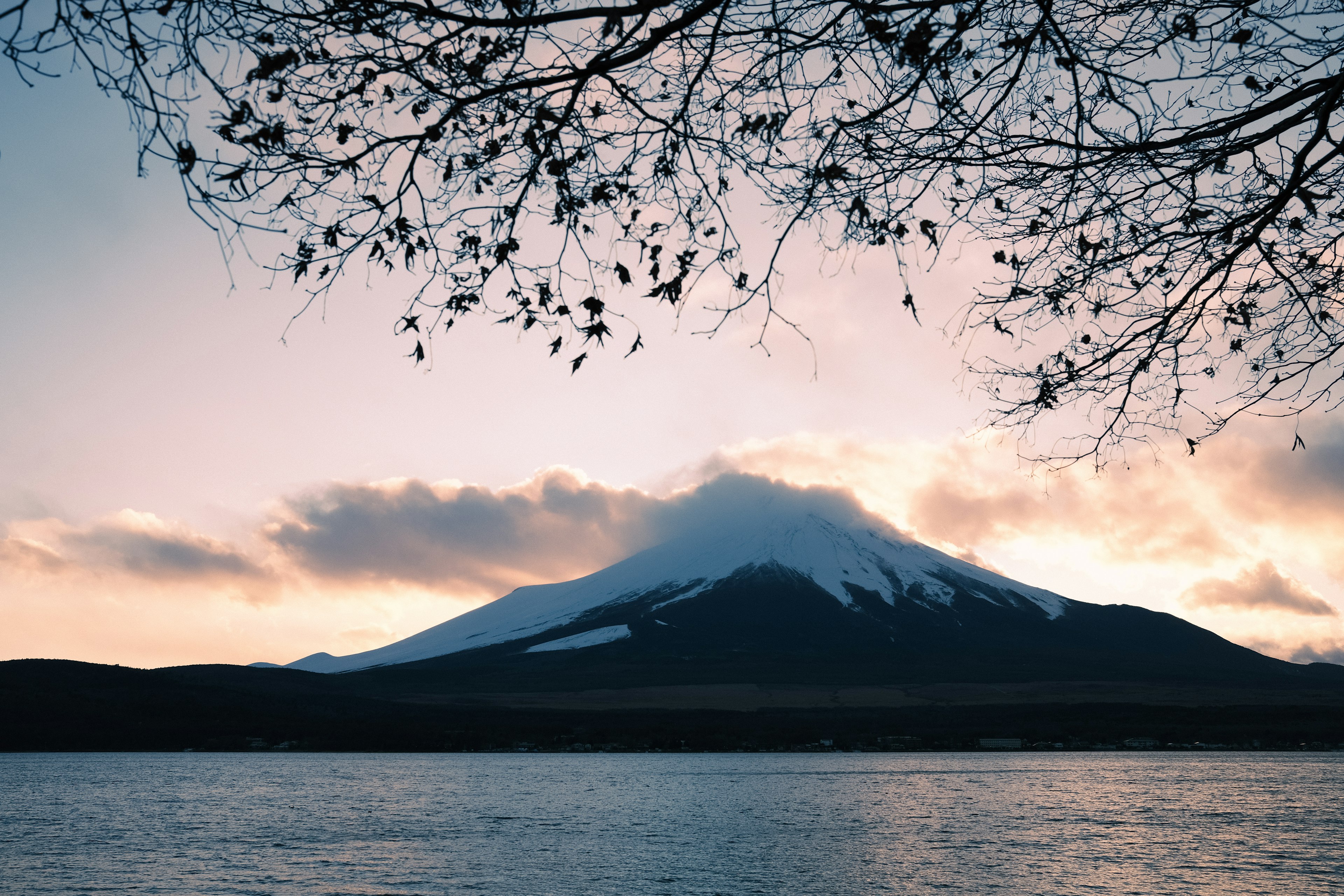 Pemandangan indah gunung dekat danau dengan puncak berkabut dan langit senja yang lembut