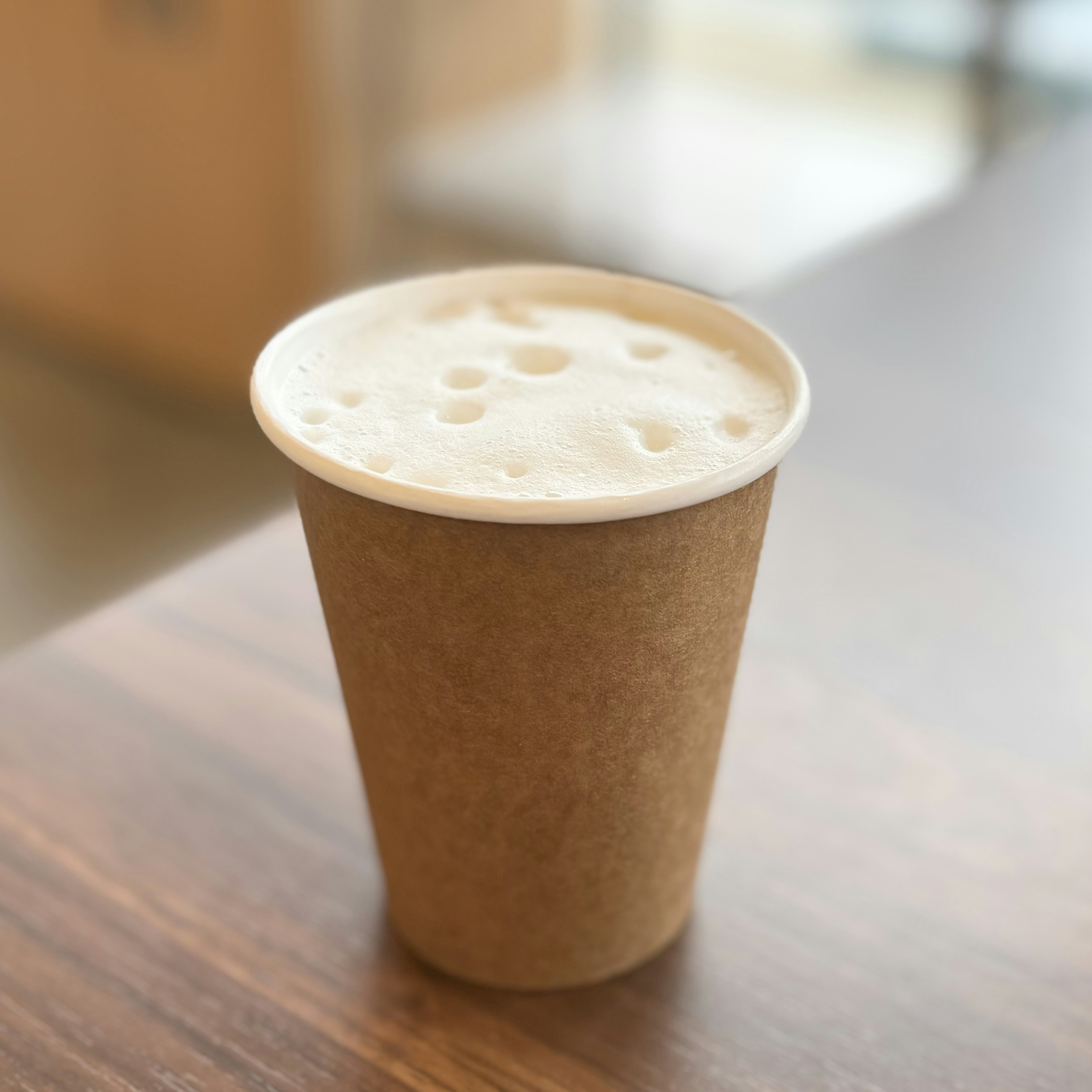 Un gobelet en papier rempli d'une boisson mousseuse posé sur une table