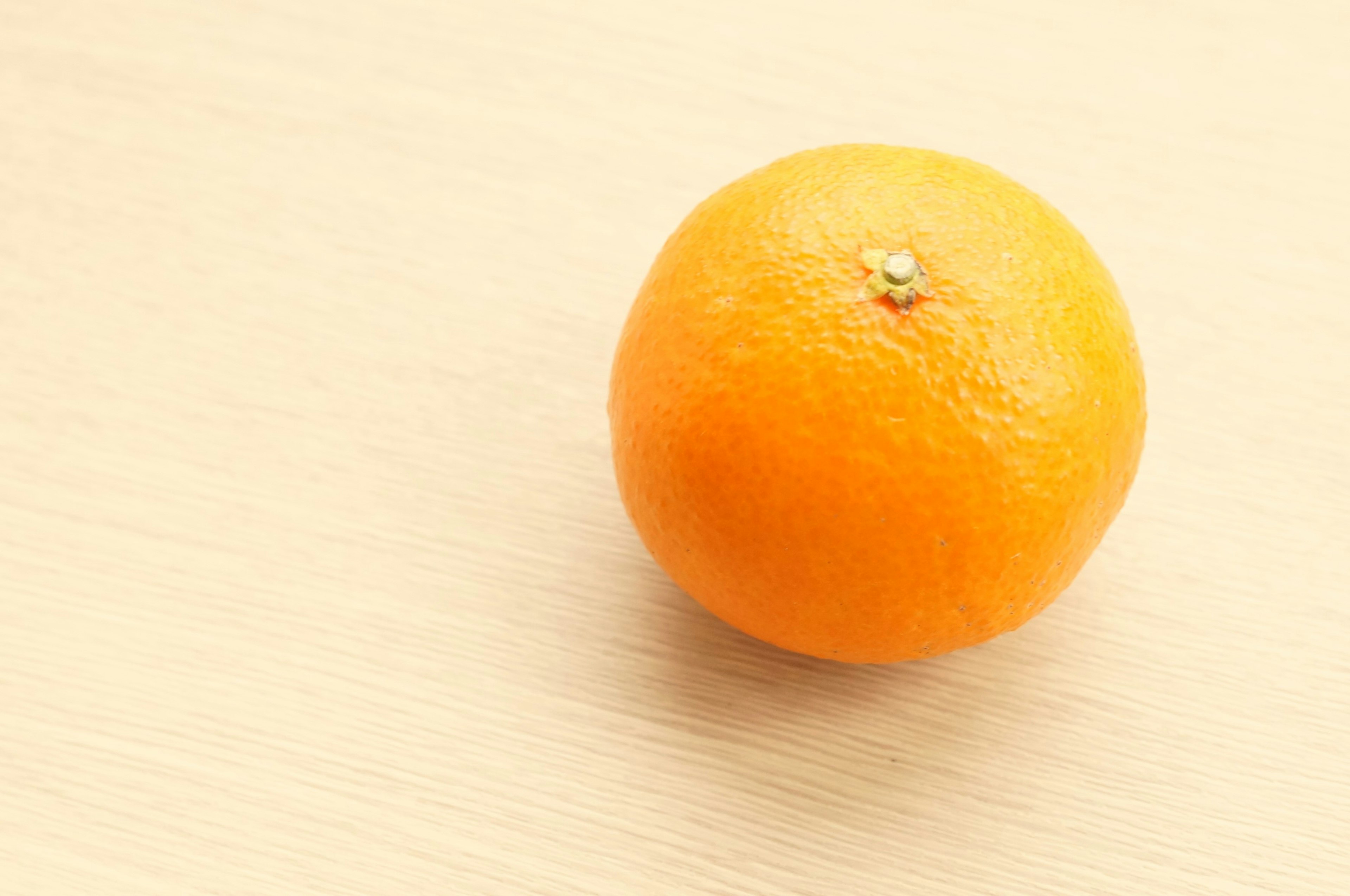 An orange fruit on a wooden table surface