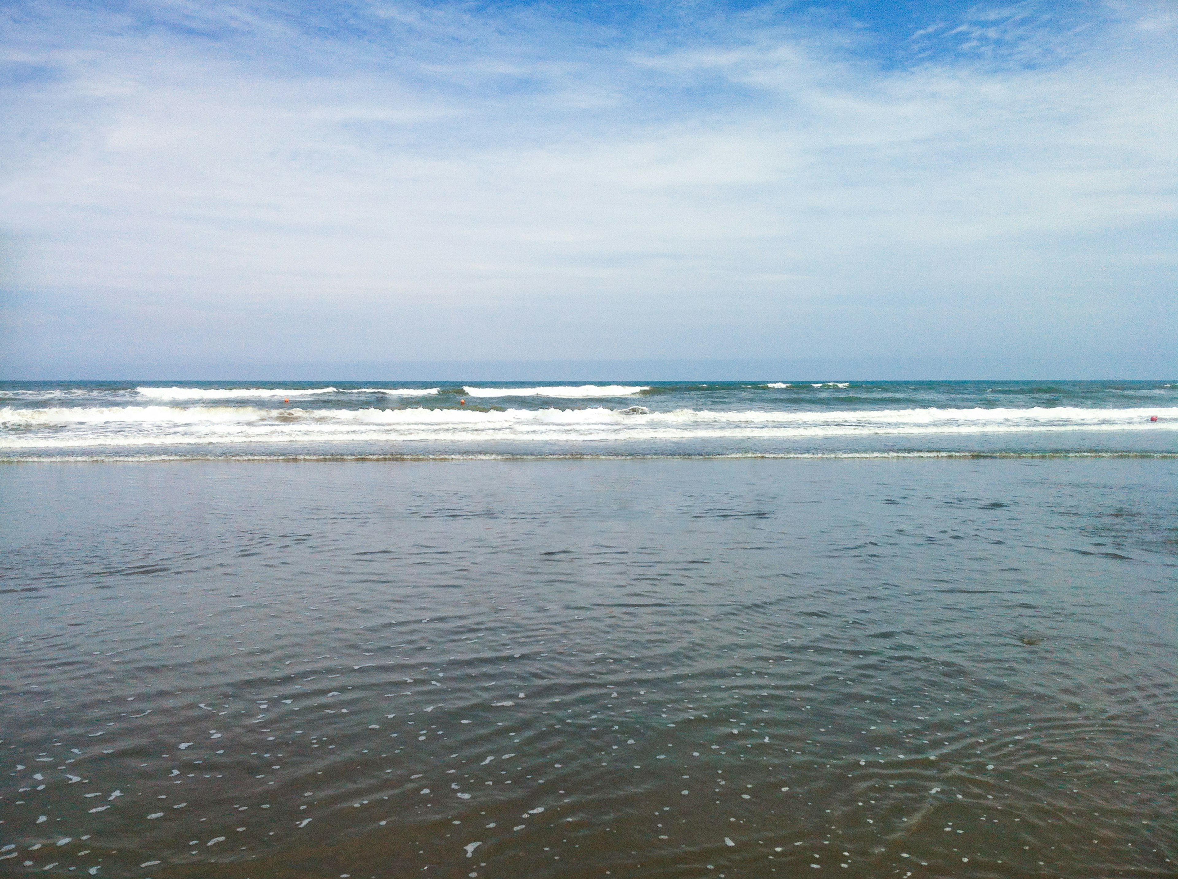 Calm beach scene with gentle waves and blue sky