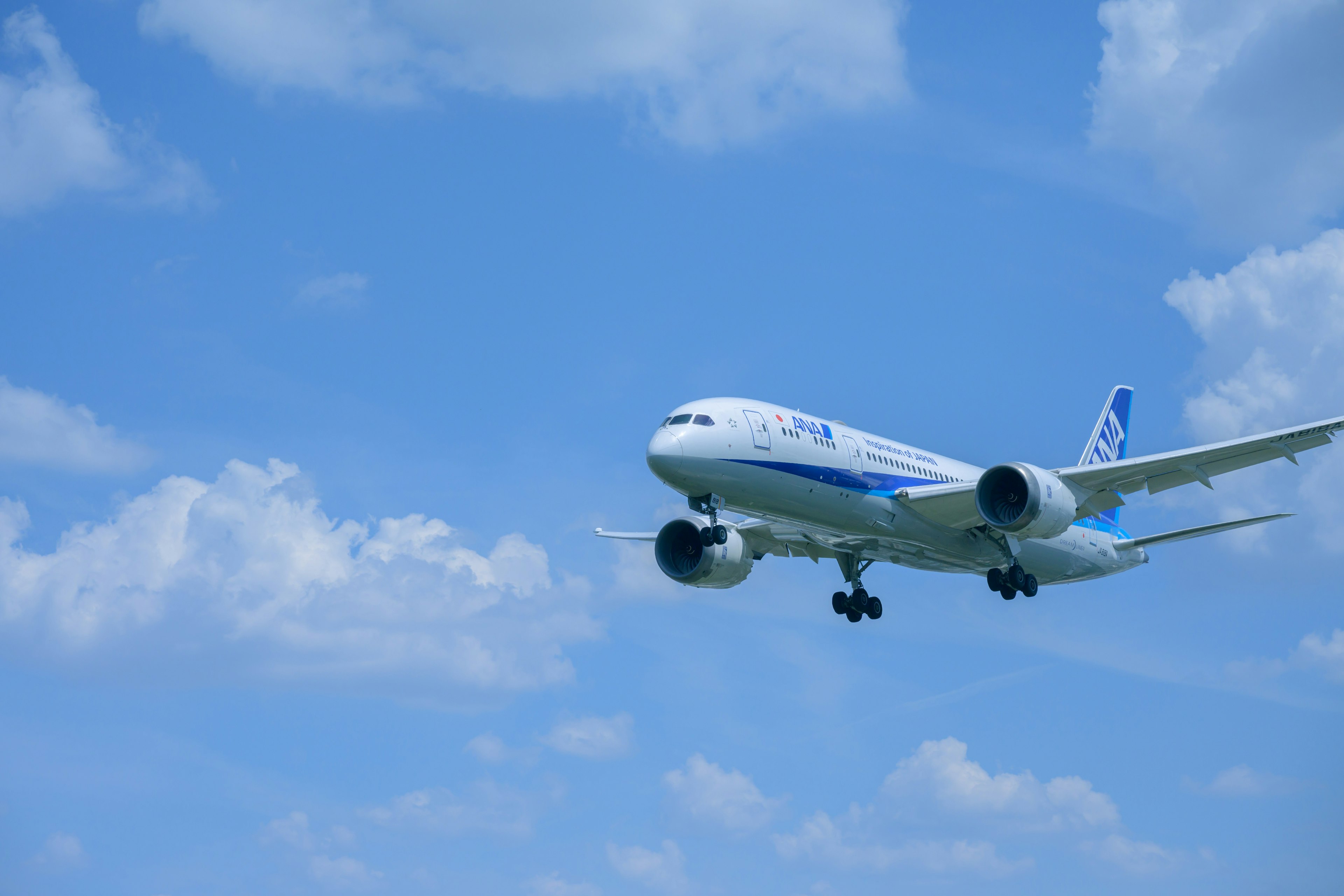 Airplane flying in a clear blue sky with white clouds