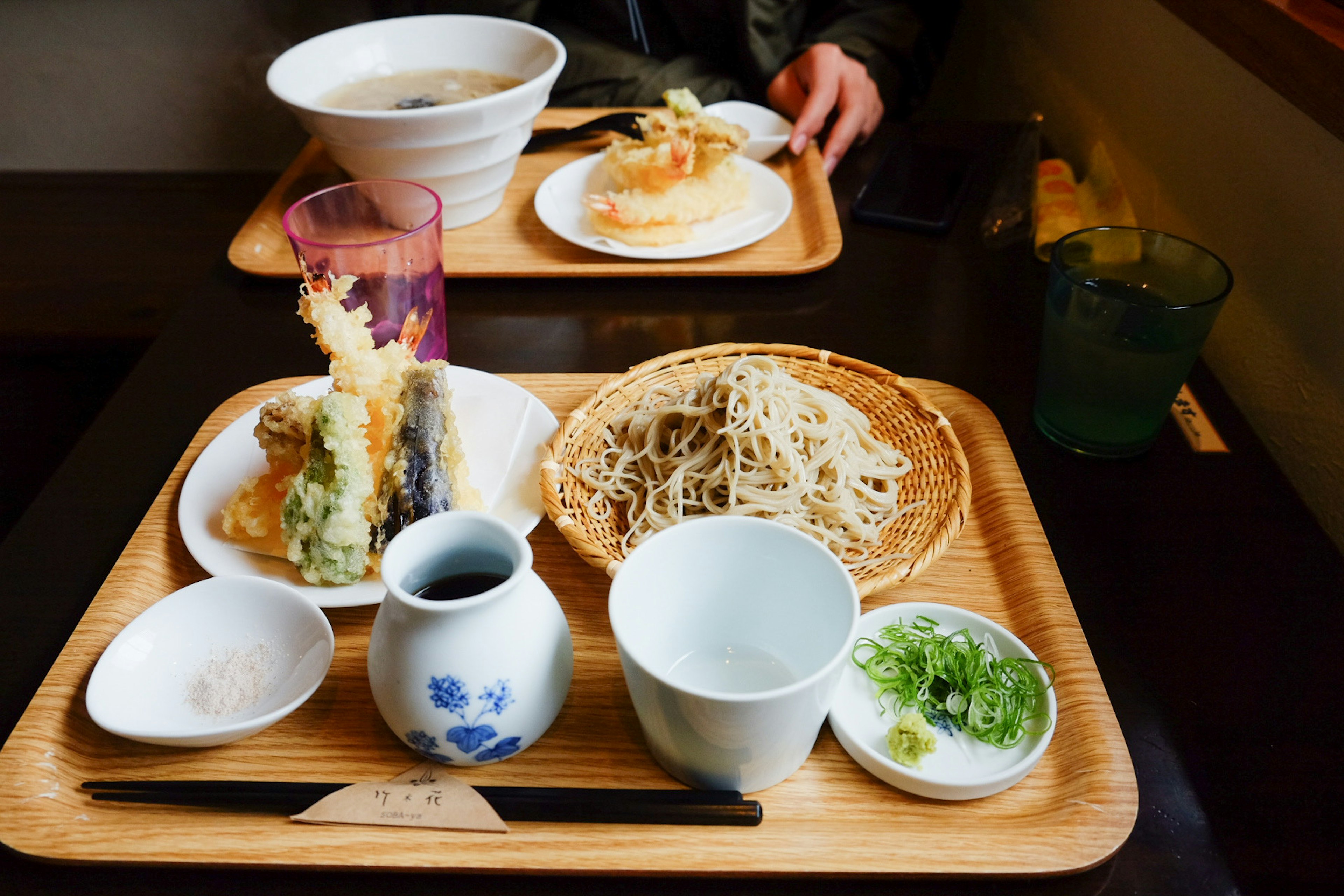 Japanese meal presentation on a table featuring tempura soba and sake with garnishes