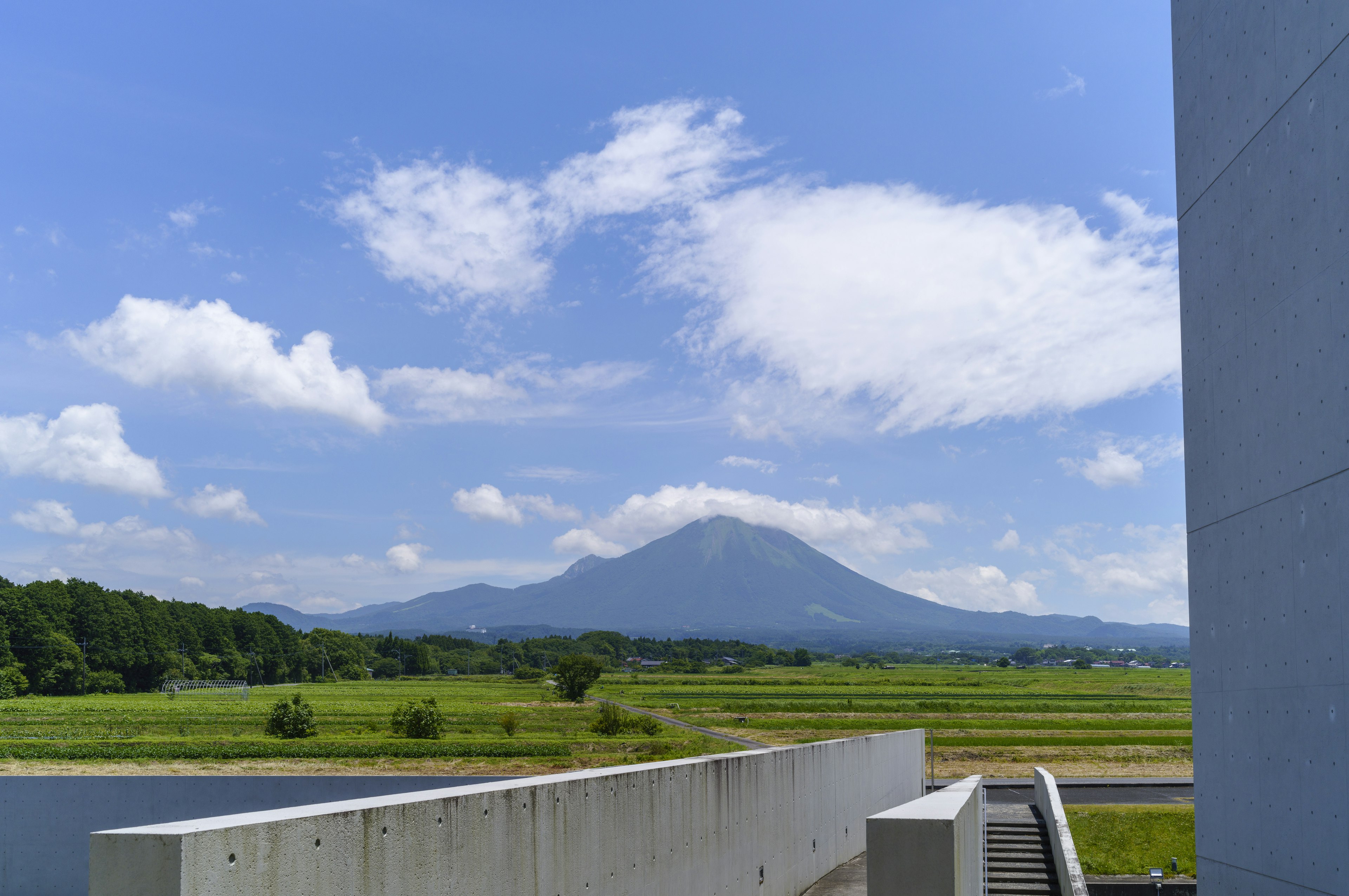 A majestic mountain under a beautiful blue sky with green fields