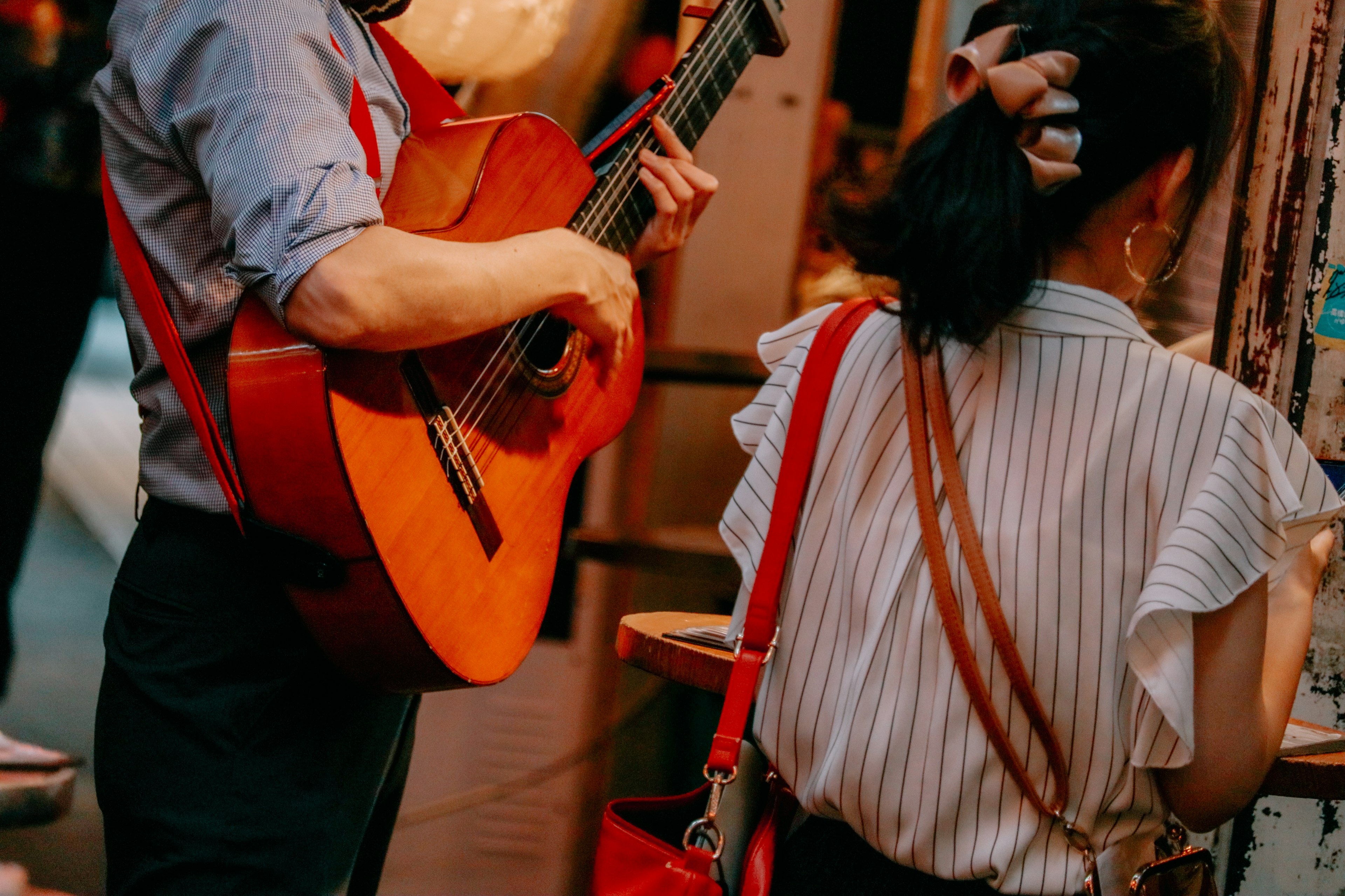 Scene with a man holding a guitar and a woman nearby colorful background with stalls and decorations