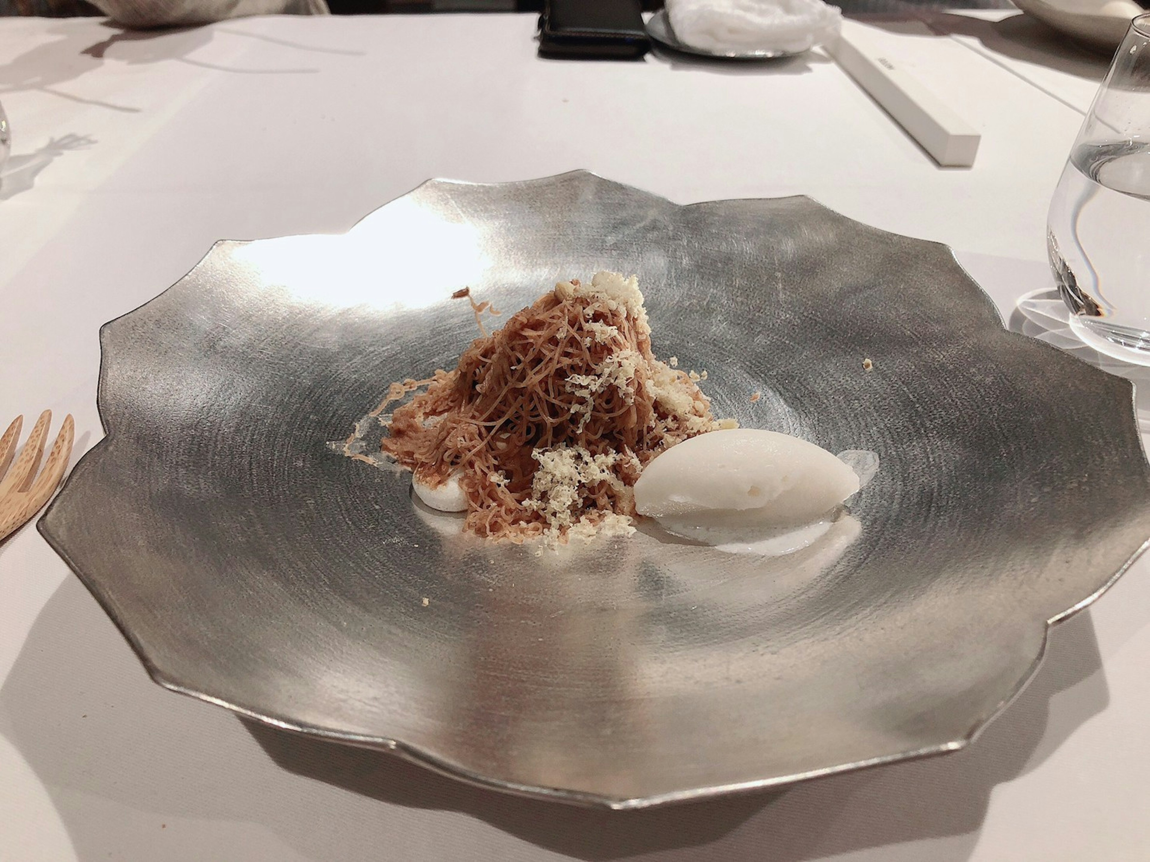 Dessert presented on a silver plate featuring a mound of ingredients and a scoop of ice cream