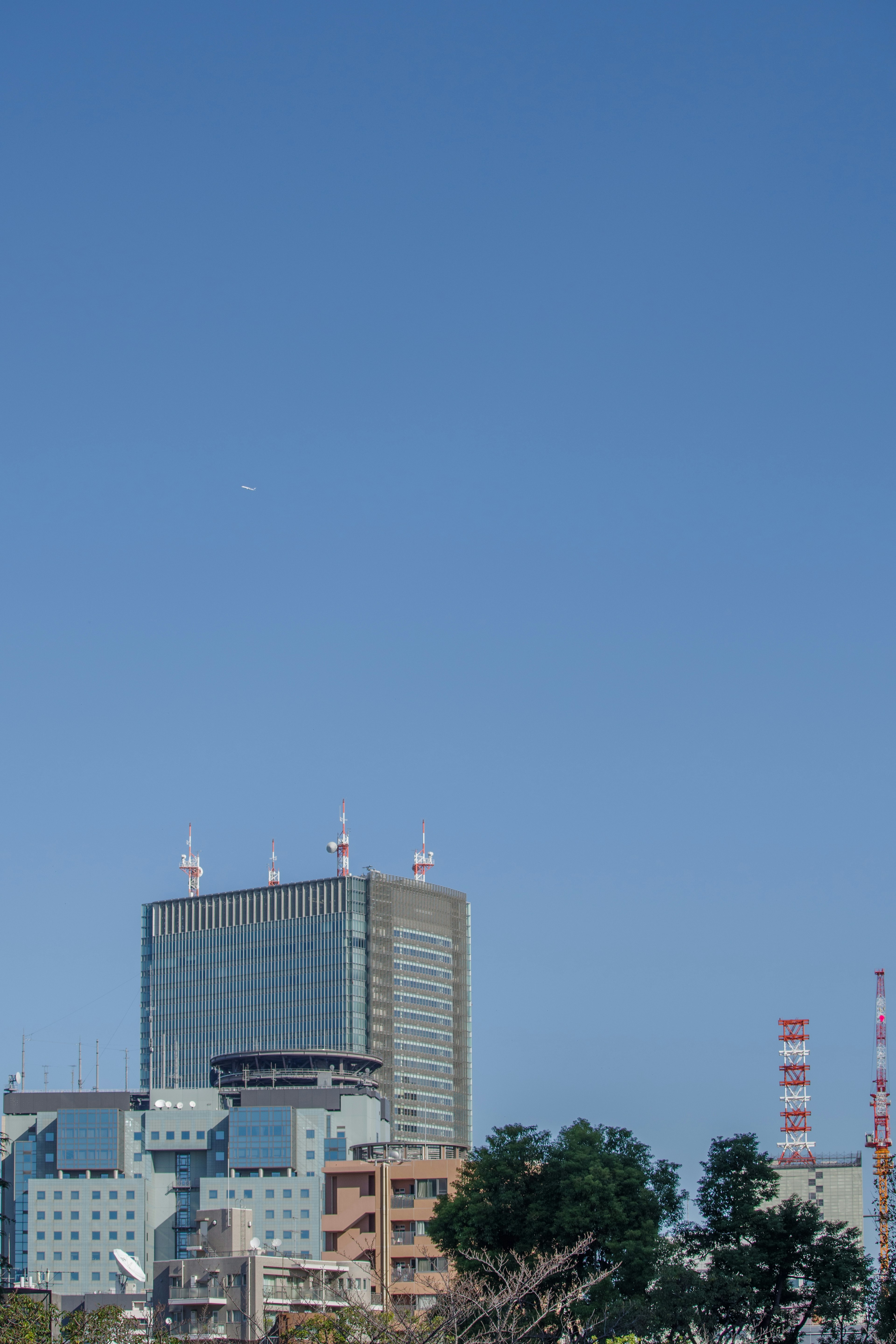 Modern skyscraper and surrounding buildings under a clear blue sky