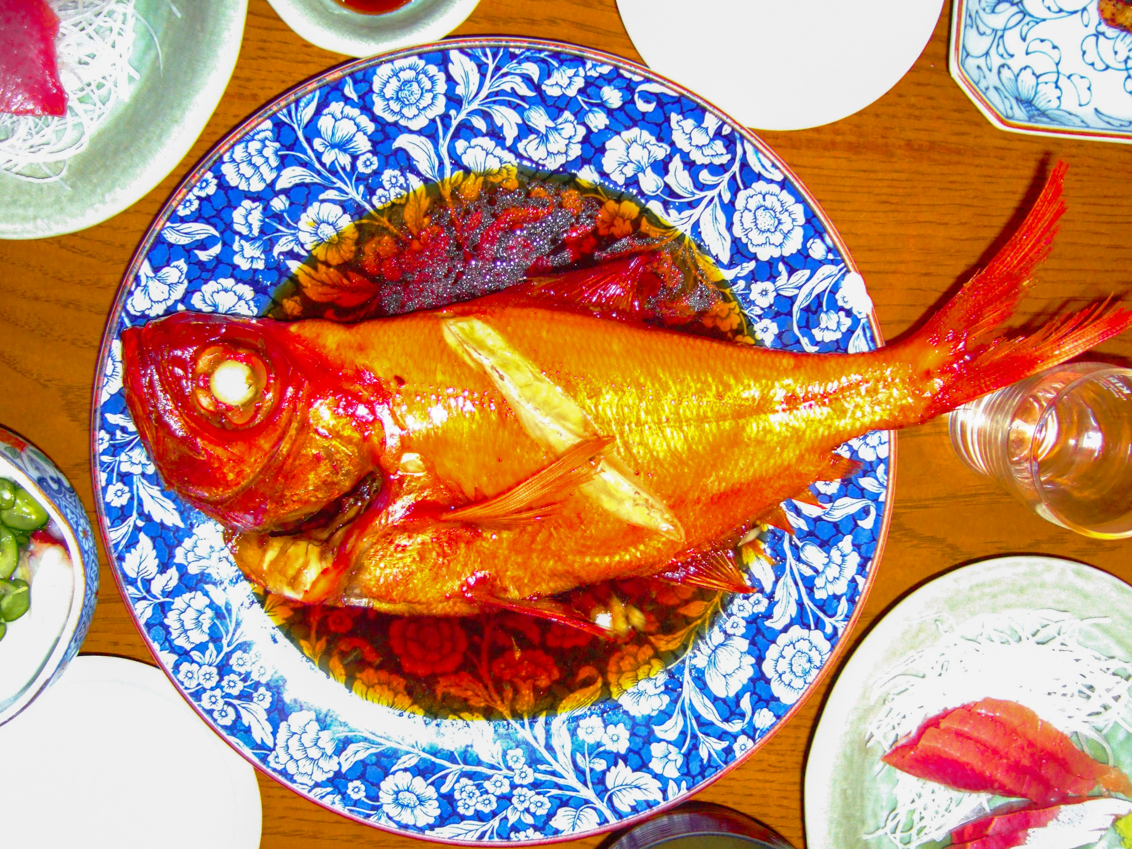 Plat de poisson doré servi sur une assiette florale bleue vibrante